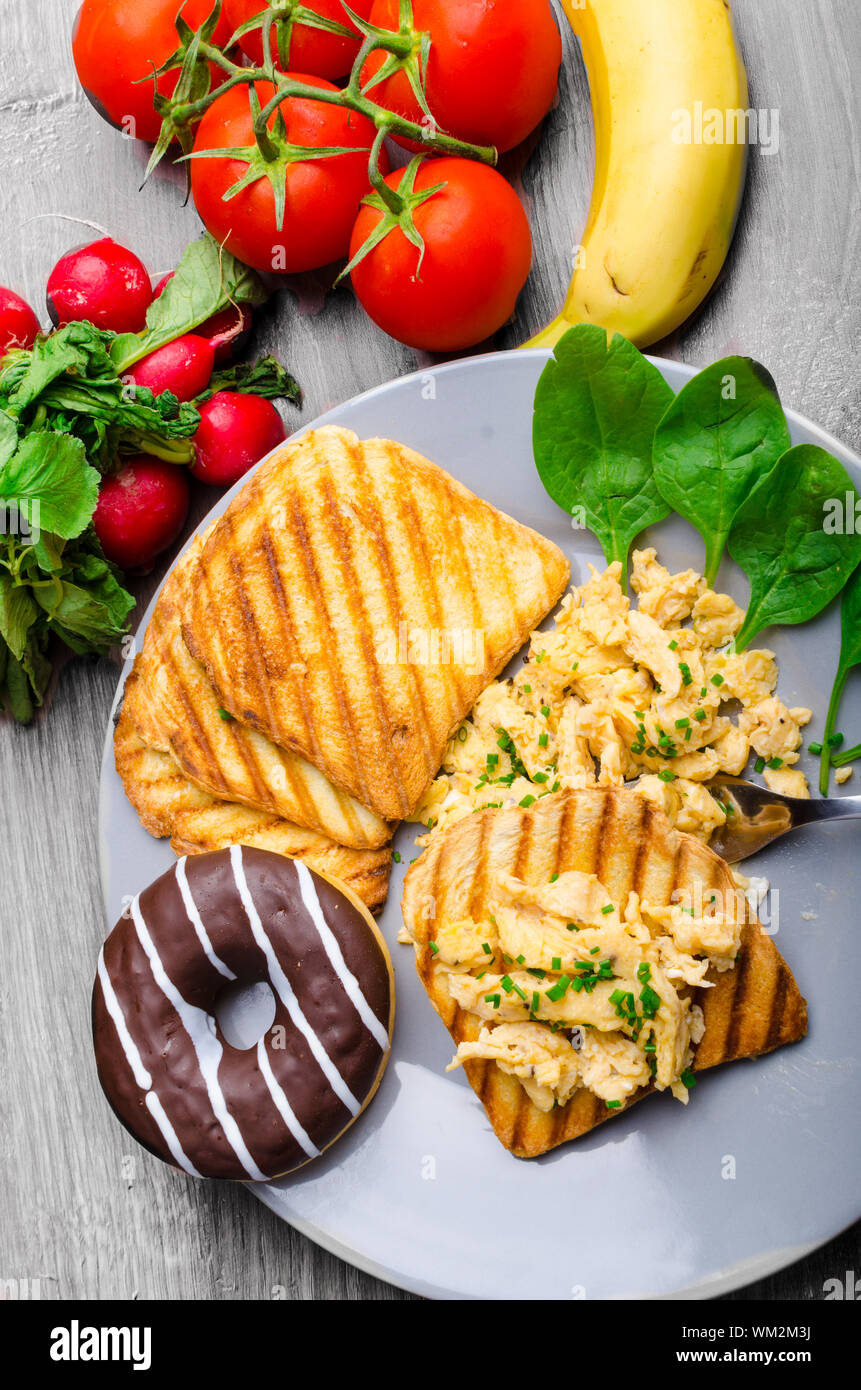 Healthy Breakfast Scrambled Eggs With Chives Panini Toast Tomatoes Radishes Banana Chocolate Donut And Fresh Spinach From The Garden Bio Stock Photo Alamy