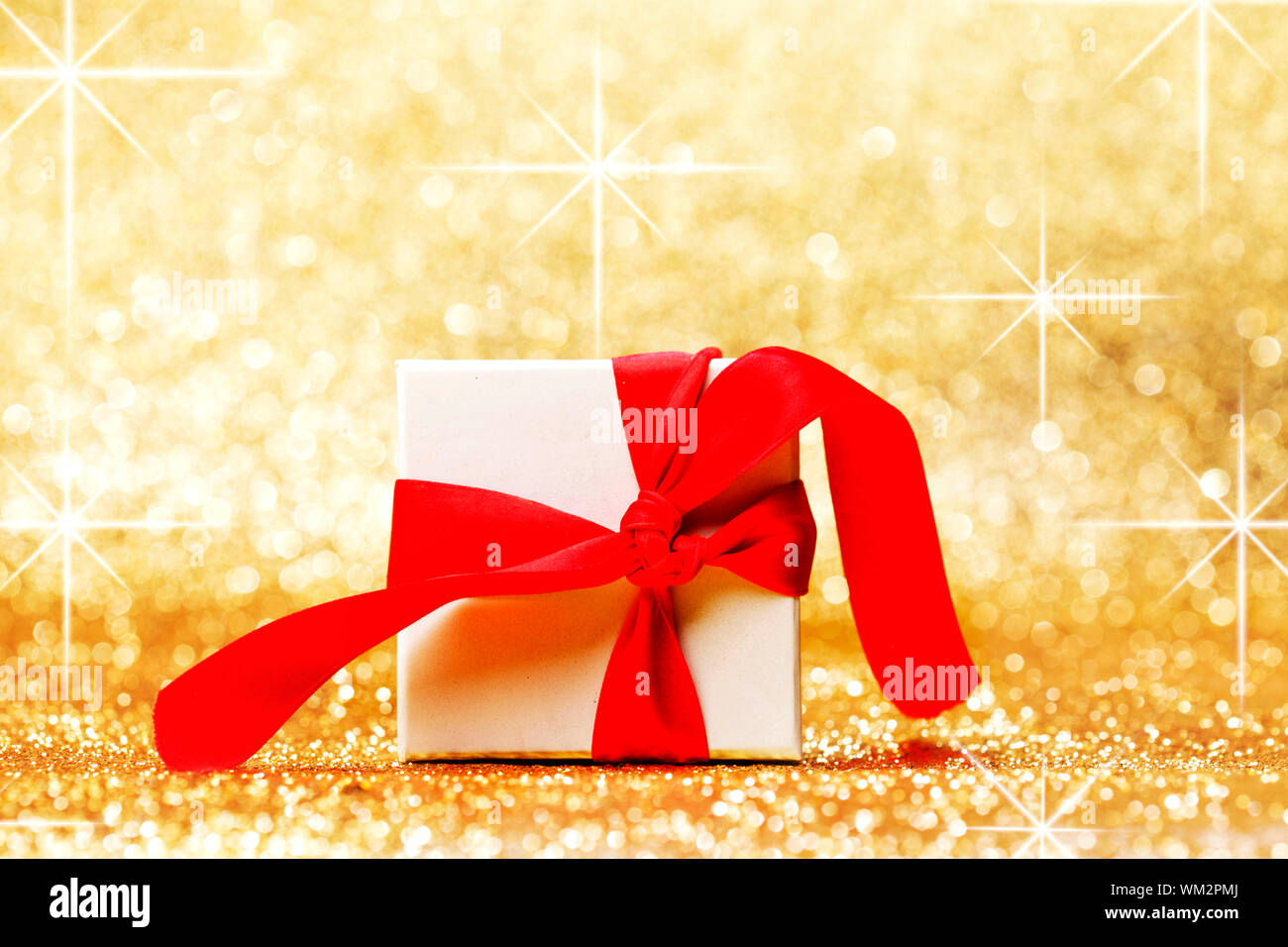 White gift box with red ribbon bow on golden glitter background Stock ...
