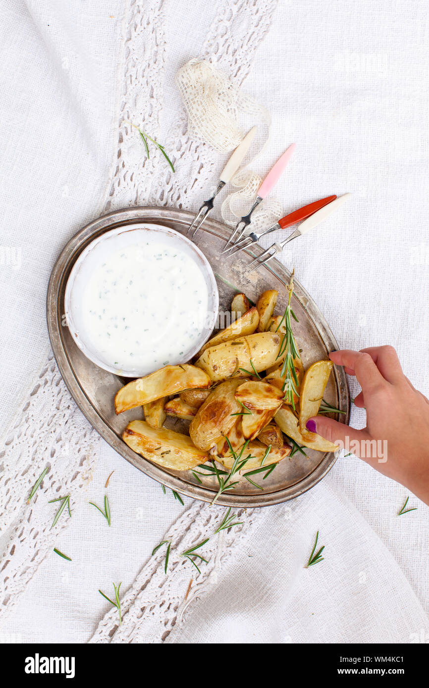 Cropped Hand Of Woman Picking Prepared Potato From Plate Stock Photo
