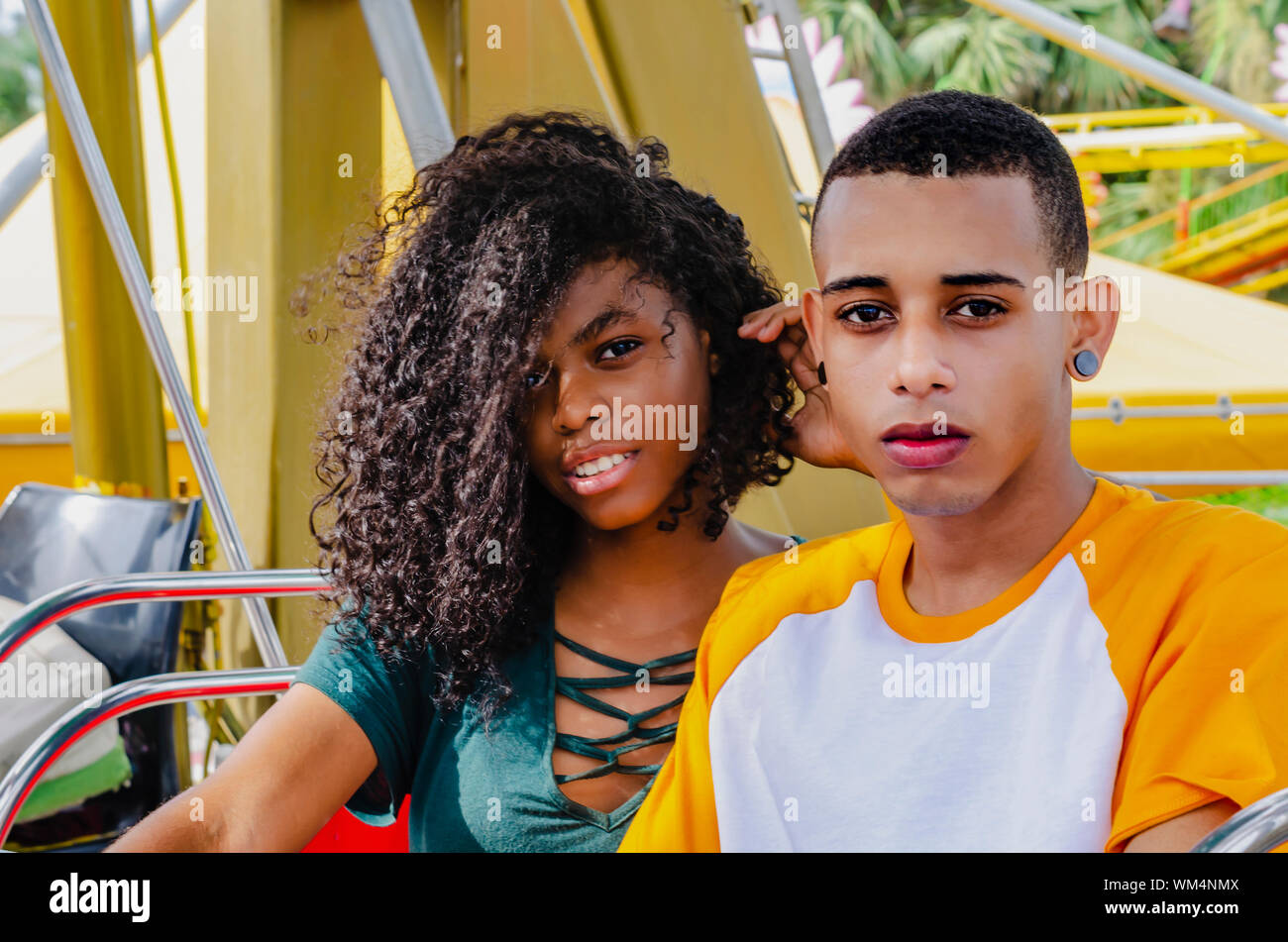 Young Latino couple sitting on a ferris wheel looking at camera Stock Photo