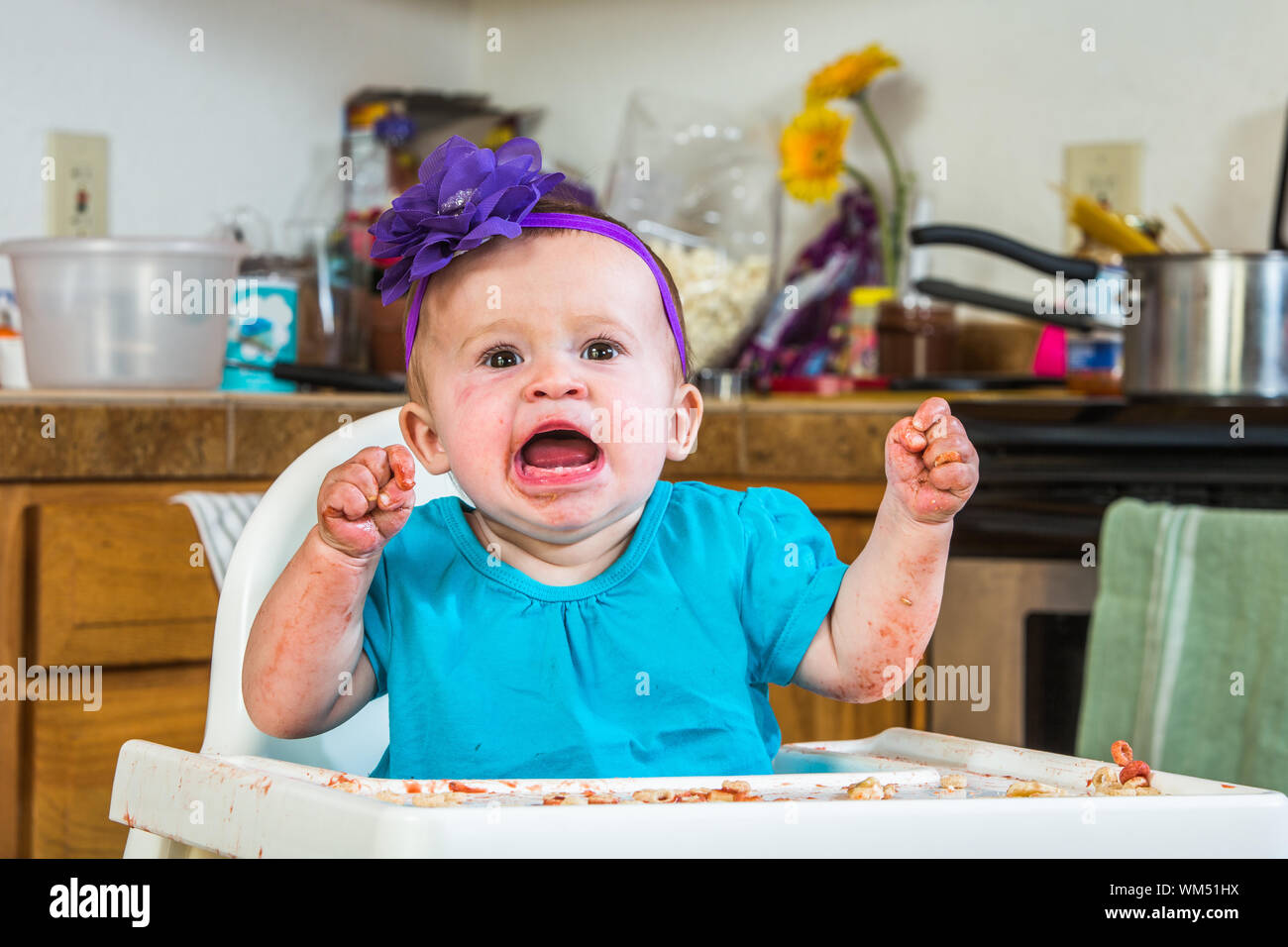 A baby girl throws a tantrum in the kitchen Stock Photo