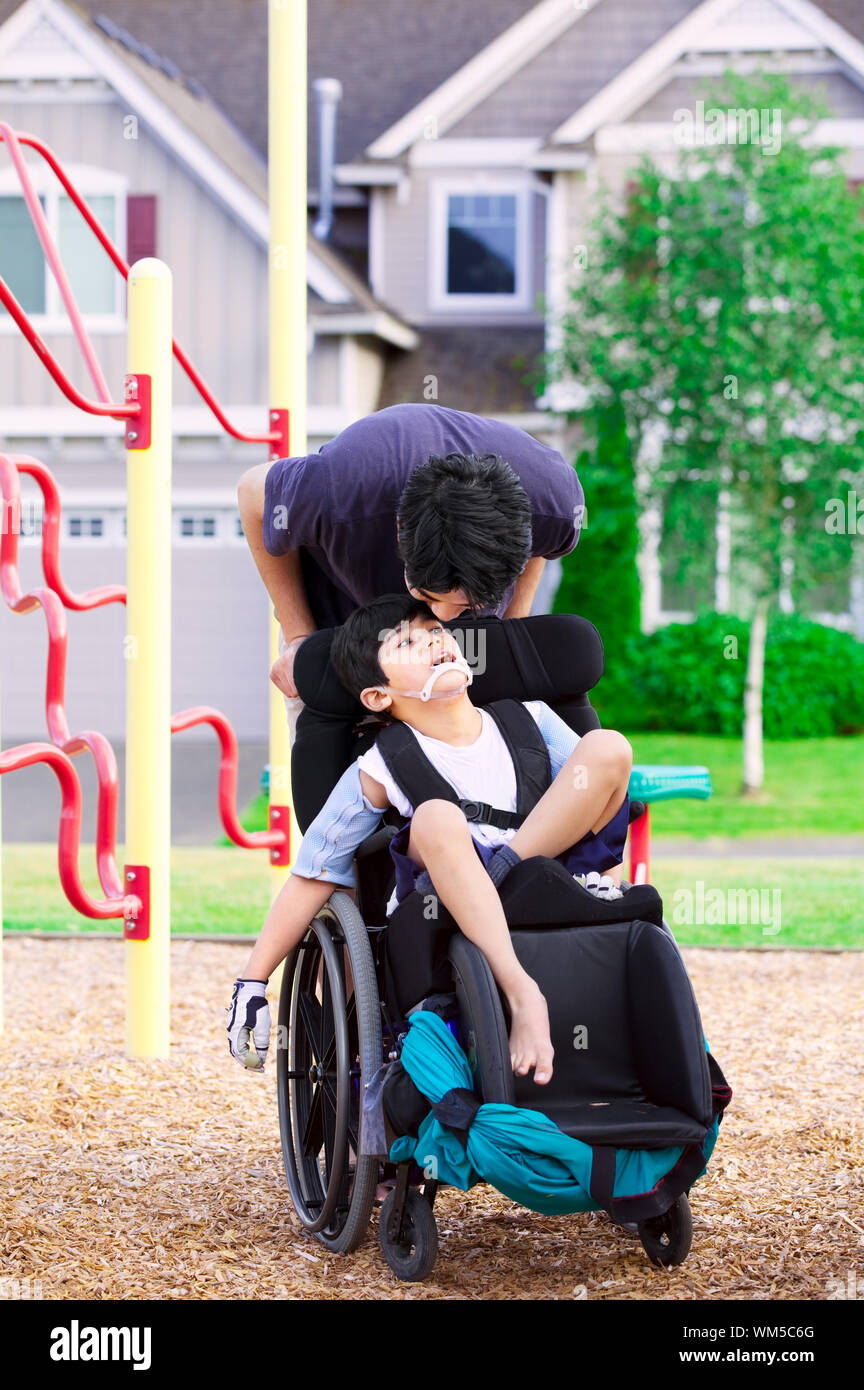 Disabled boy in wheelchair with big brother at park Stock Photo