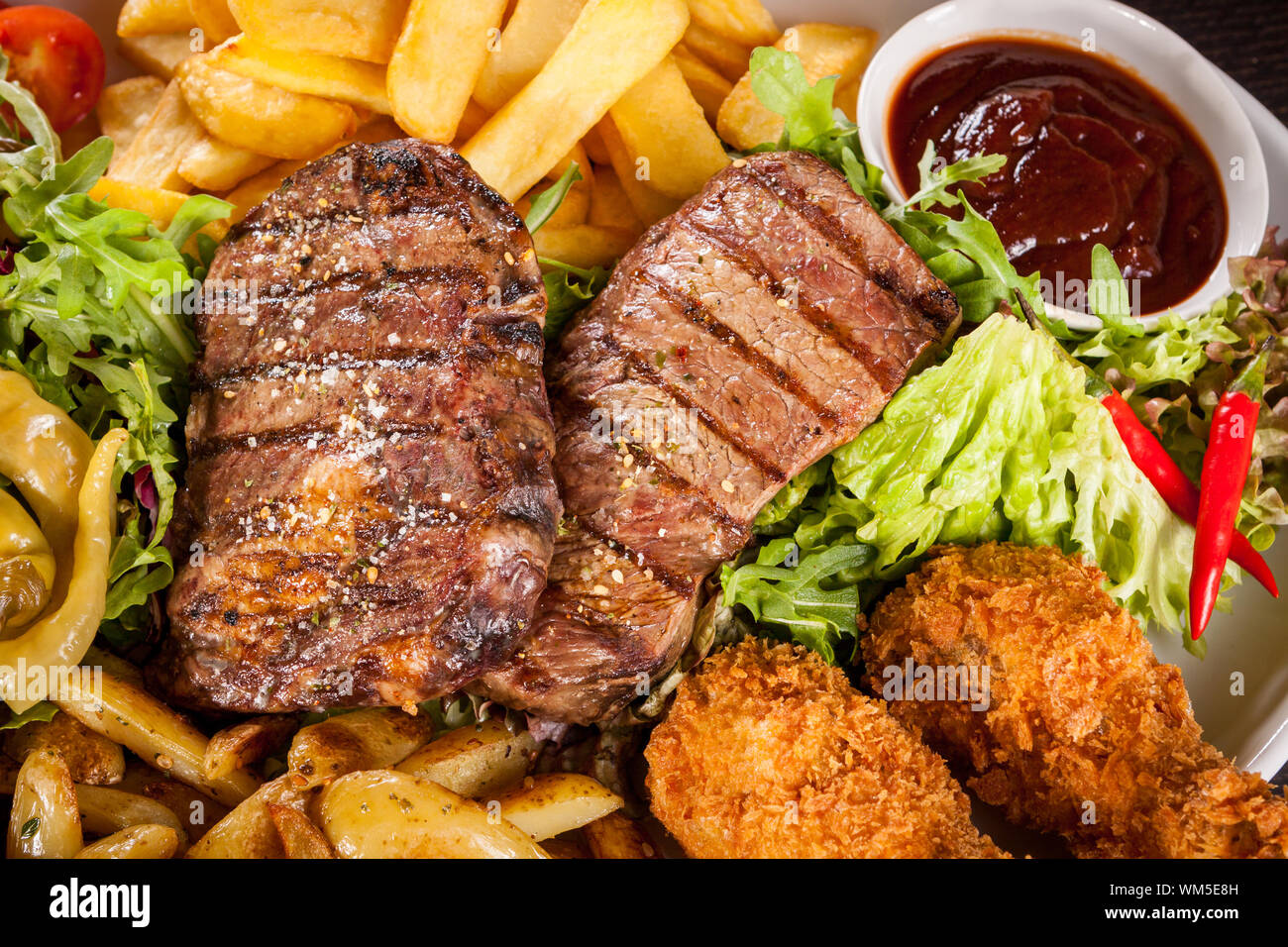 Platter of mixed meats, salad and French fries Stock Photo