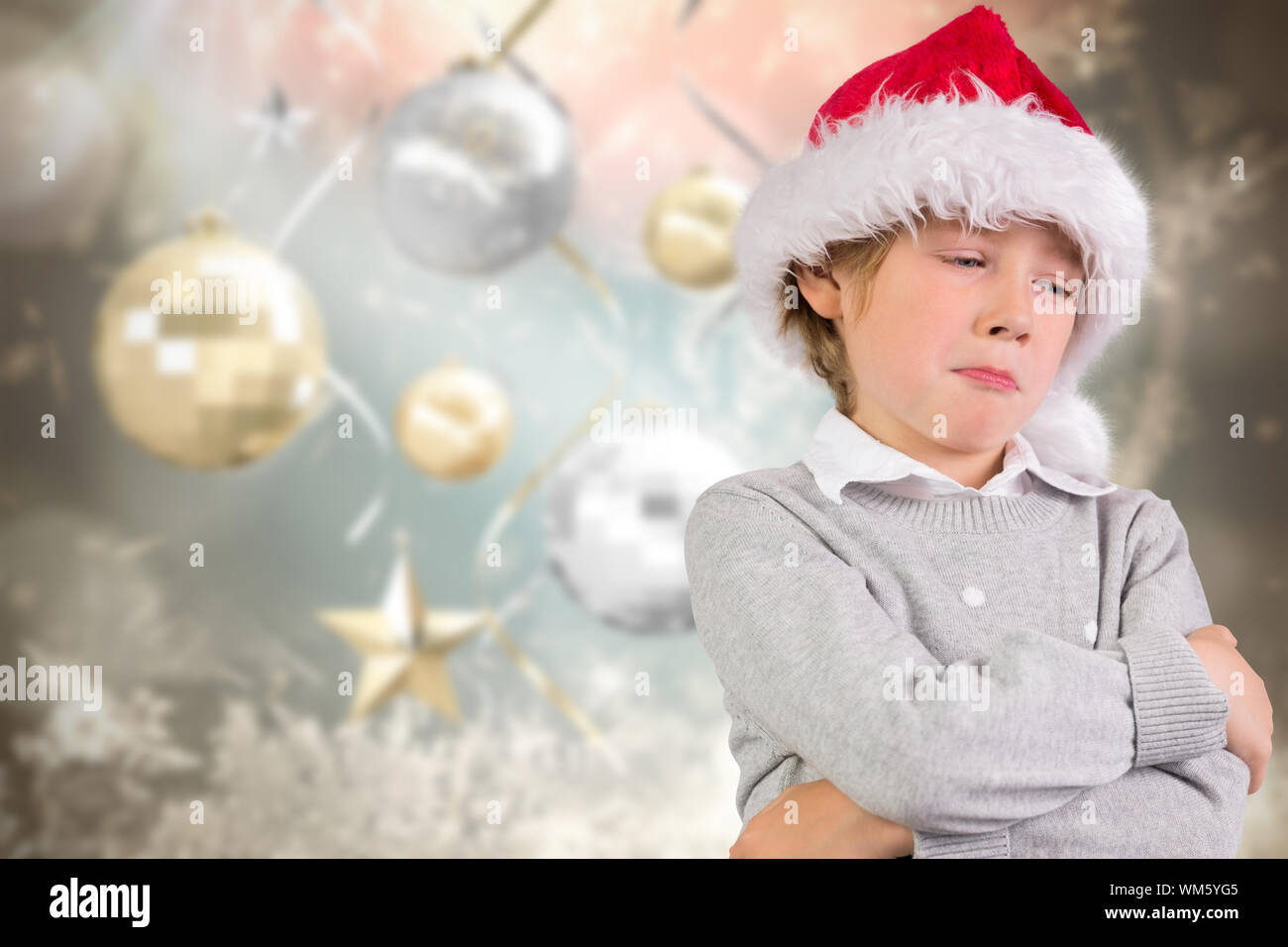 Festive boy sulking against blurred christmas background Stock Photo