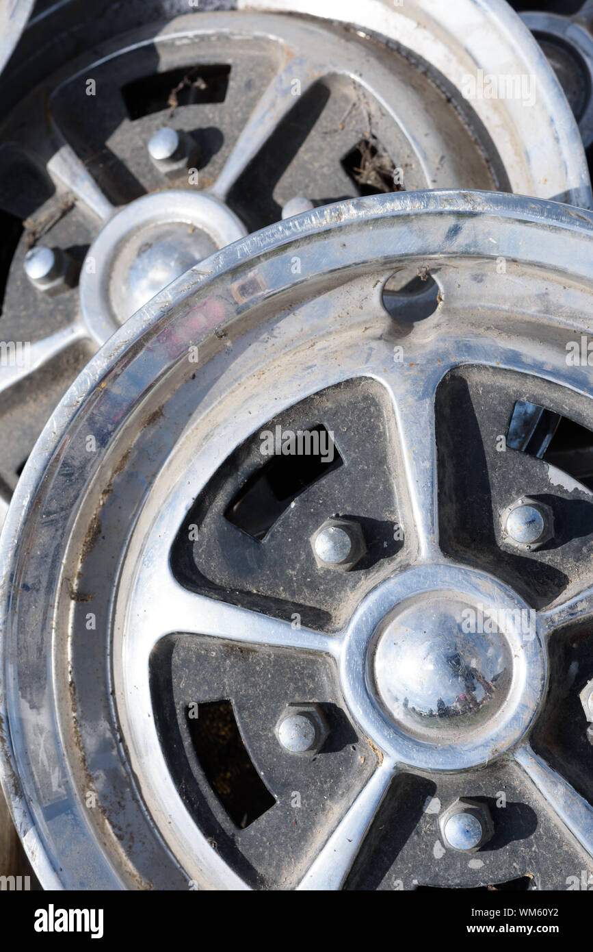Closeup of tow car wheel trims in alloy metal silver with dirt and grime showing their used condition Stock Photo