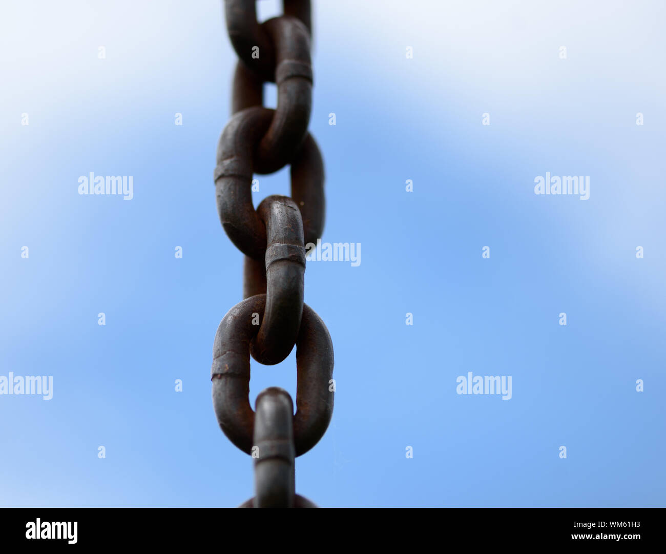 Metal chain in a closeup view with blue sky and clouds with copyspace area for freedom slavery persecution based design s and ideas Stock Photo