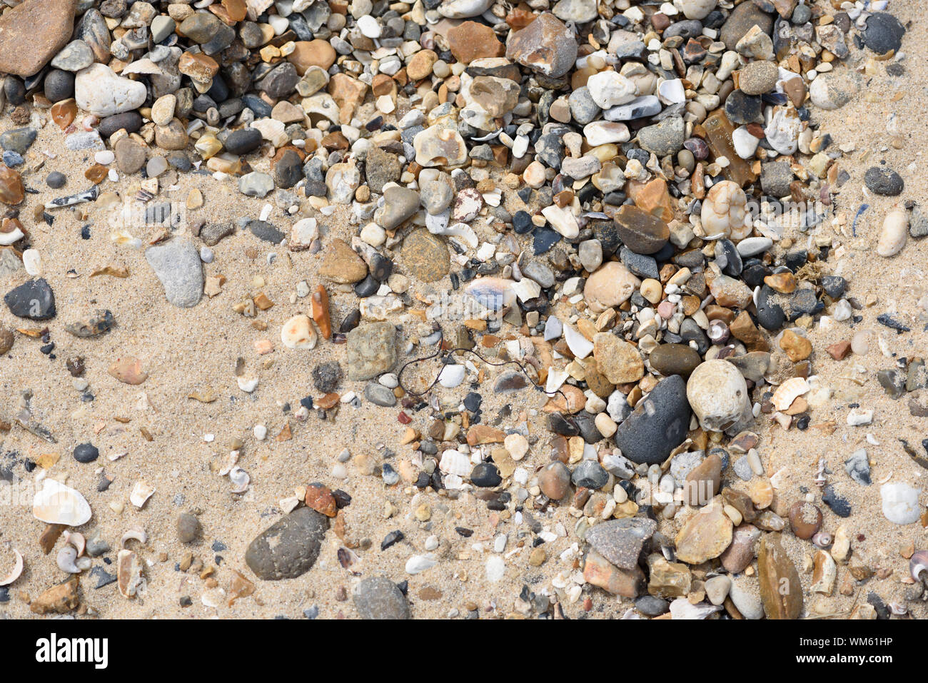Pebbles and sand merge together on the sides of a sea coastal water area Stock Photo