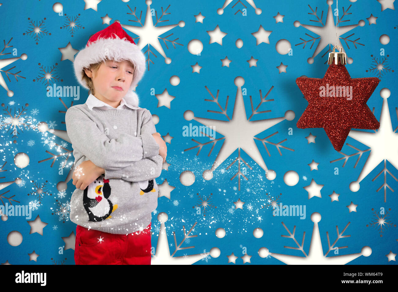 Festive boy sulking against snowflake wallpaper pattern Stock Photo