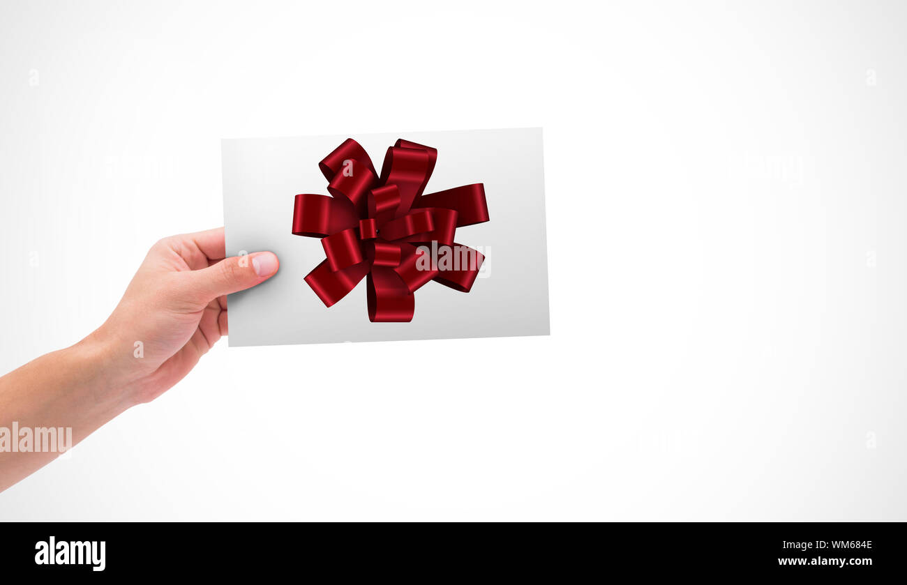 Hand holding card against red christmas bow for gift Stock Photo - Alamy