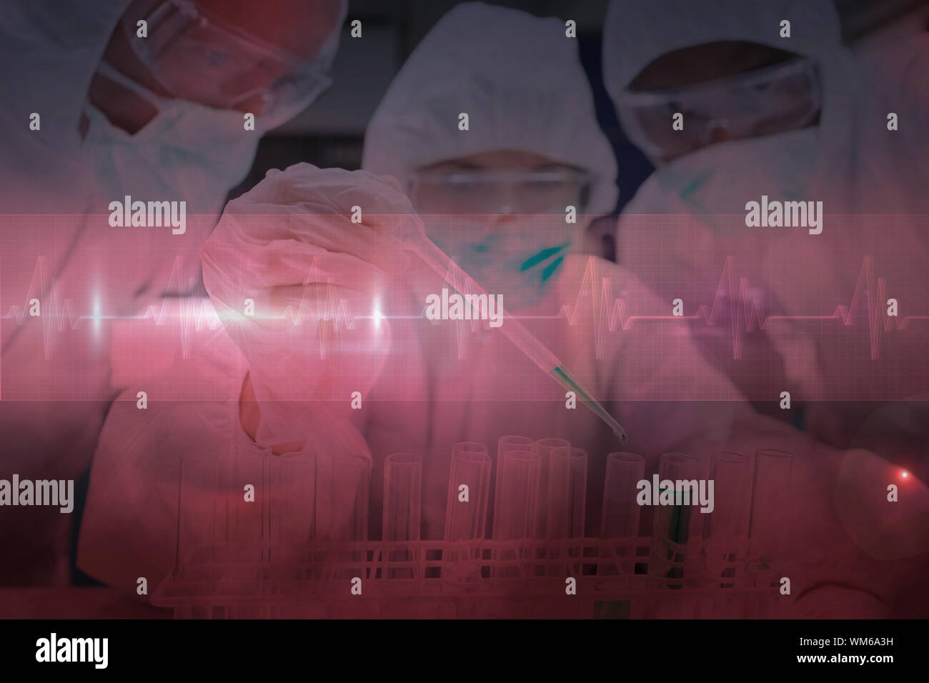 Chemist adding green liquid to test tubes as two others are watching