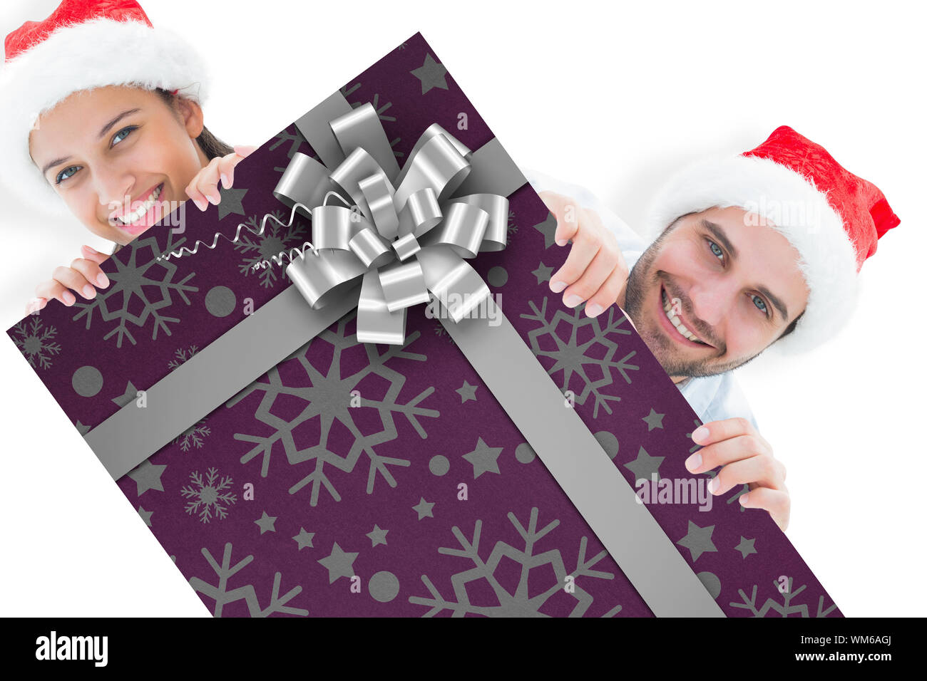 Festive young couple smiling at camera against christmas wrapping paper with bow Stock Photo - Alamy