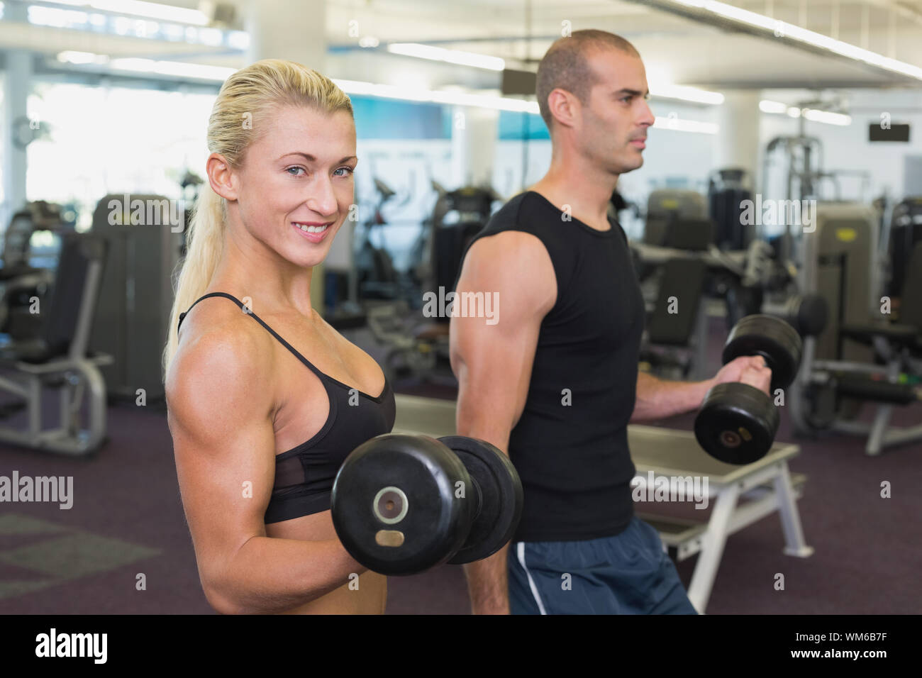 Side view of a couple exercising with dumbbells in the gym Stock Photo ...