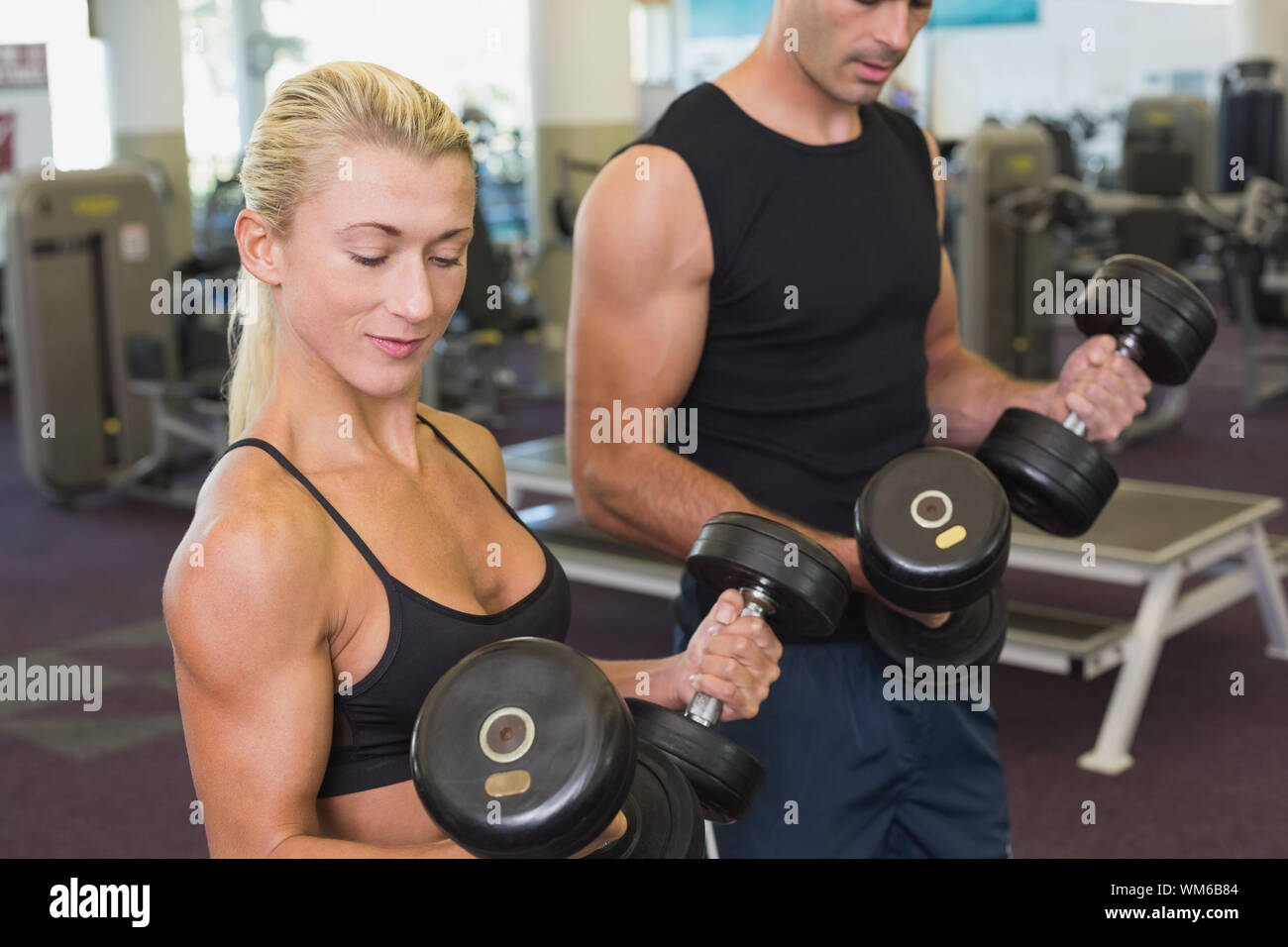 Side view of a couple exercising with dumbbells in the gym Stock Photo ...