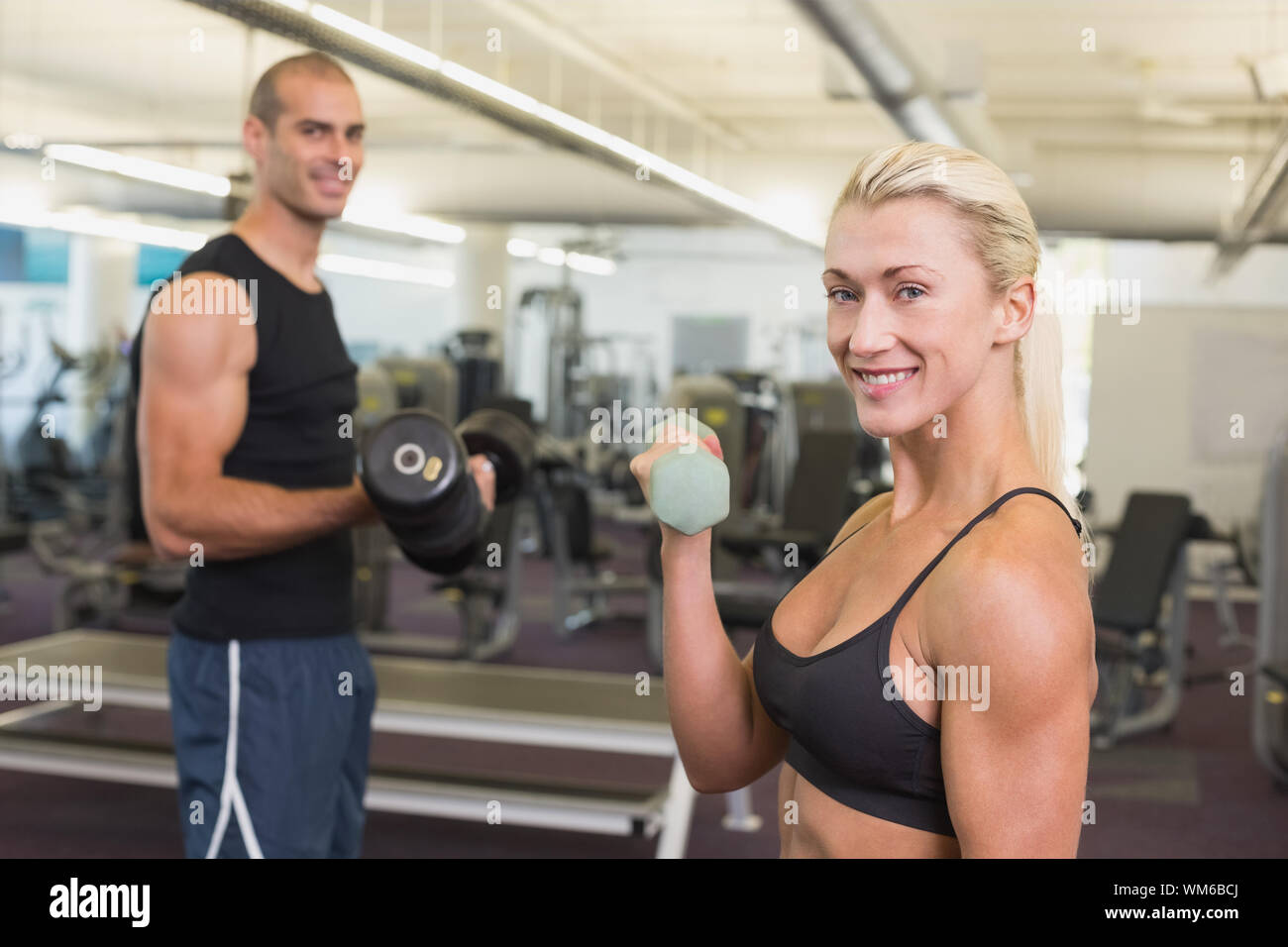 Side view of a couple exercising with dumbbells in the gym Stock Photo ...