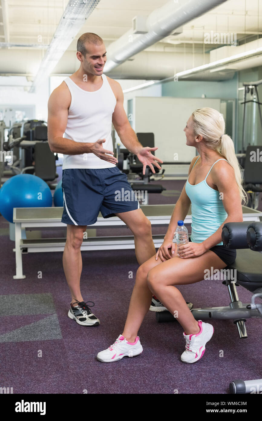 Smiling male trainer talking to fit young woman at the gym Stock Photo ...