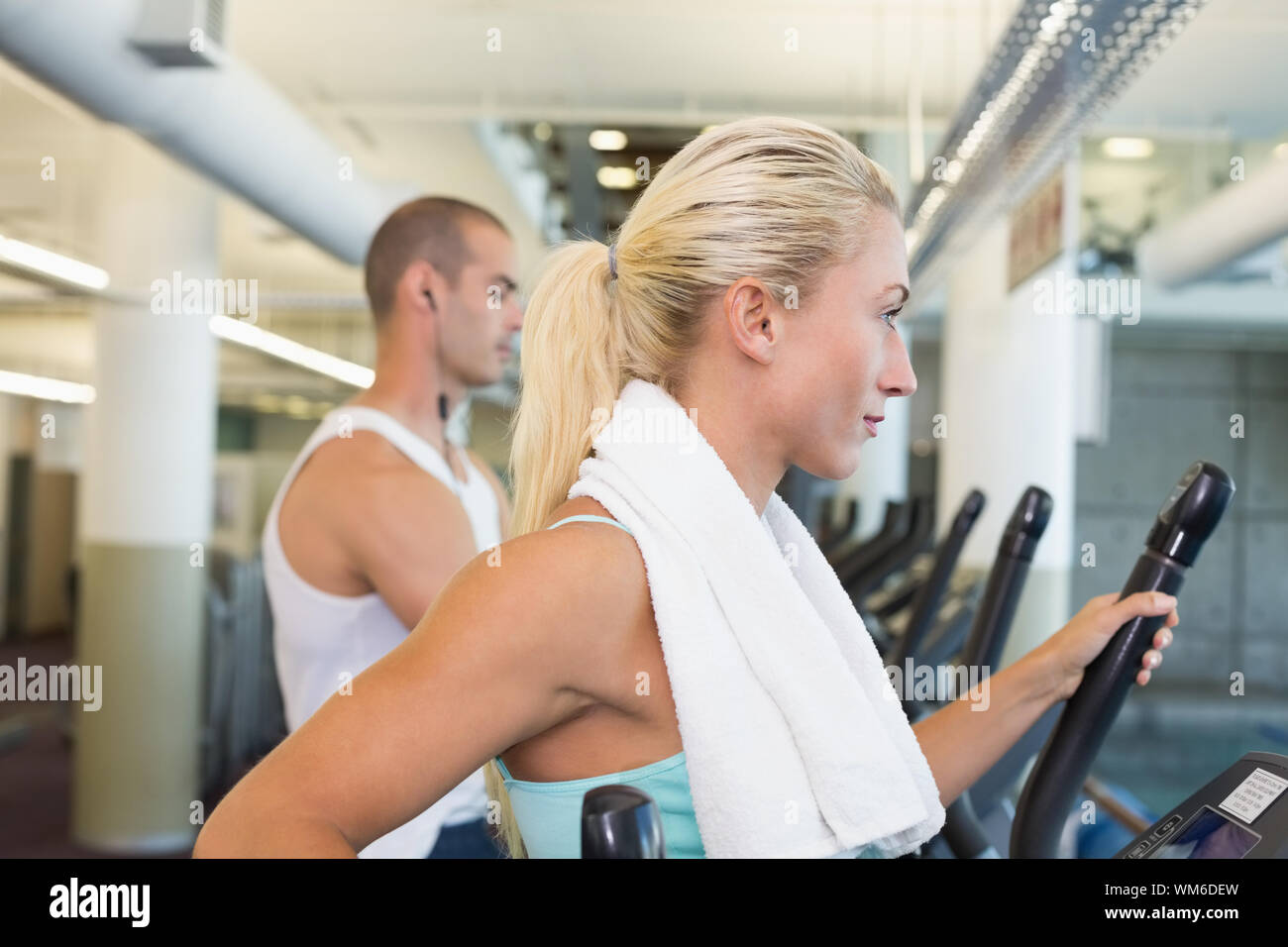Side view of a fit young couple working on x-trainers at the gym Stock ...