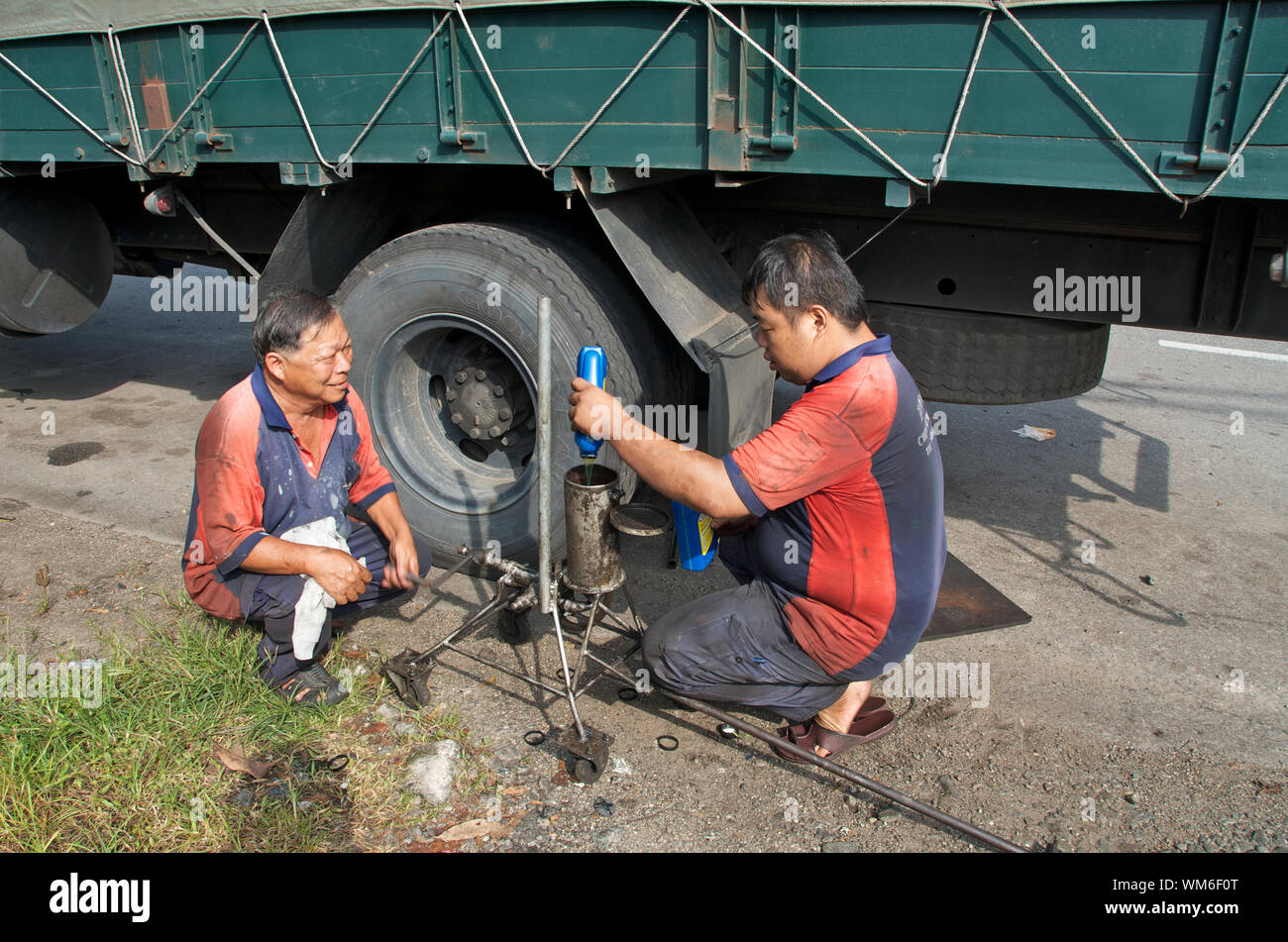 Chinese Mechanics Repair A Puncture On A Truck Carrying Palm Fruit In Malaysia Stock Photo Alamy