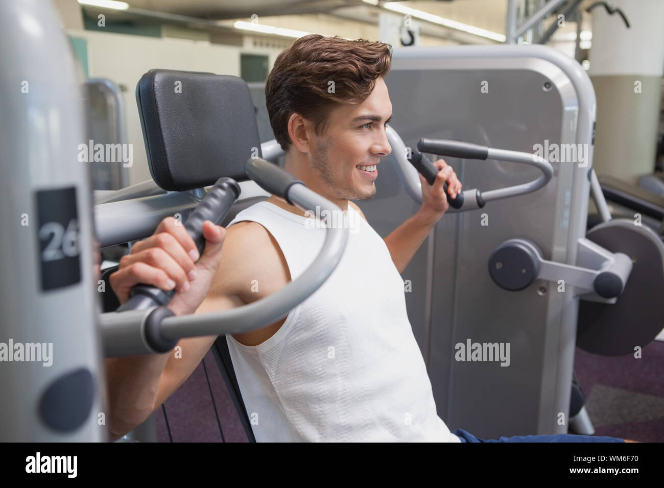 Gym Machine Using Arms Fit man using weights machine for arms at the gym Stock Photo - Alamy