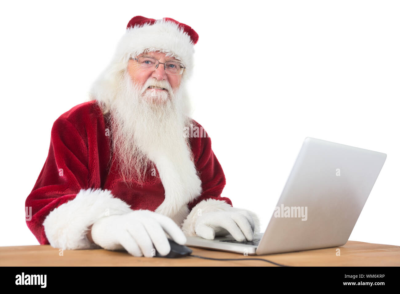 Santa surfs on the internet at a desk on white background Stock Photo ...