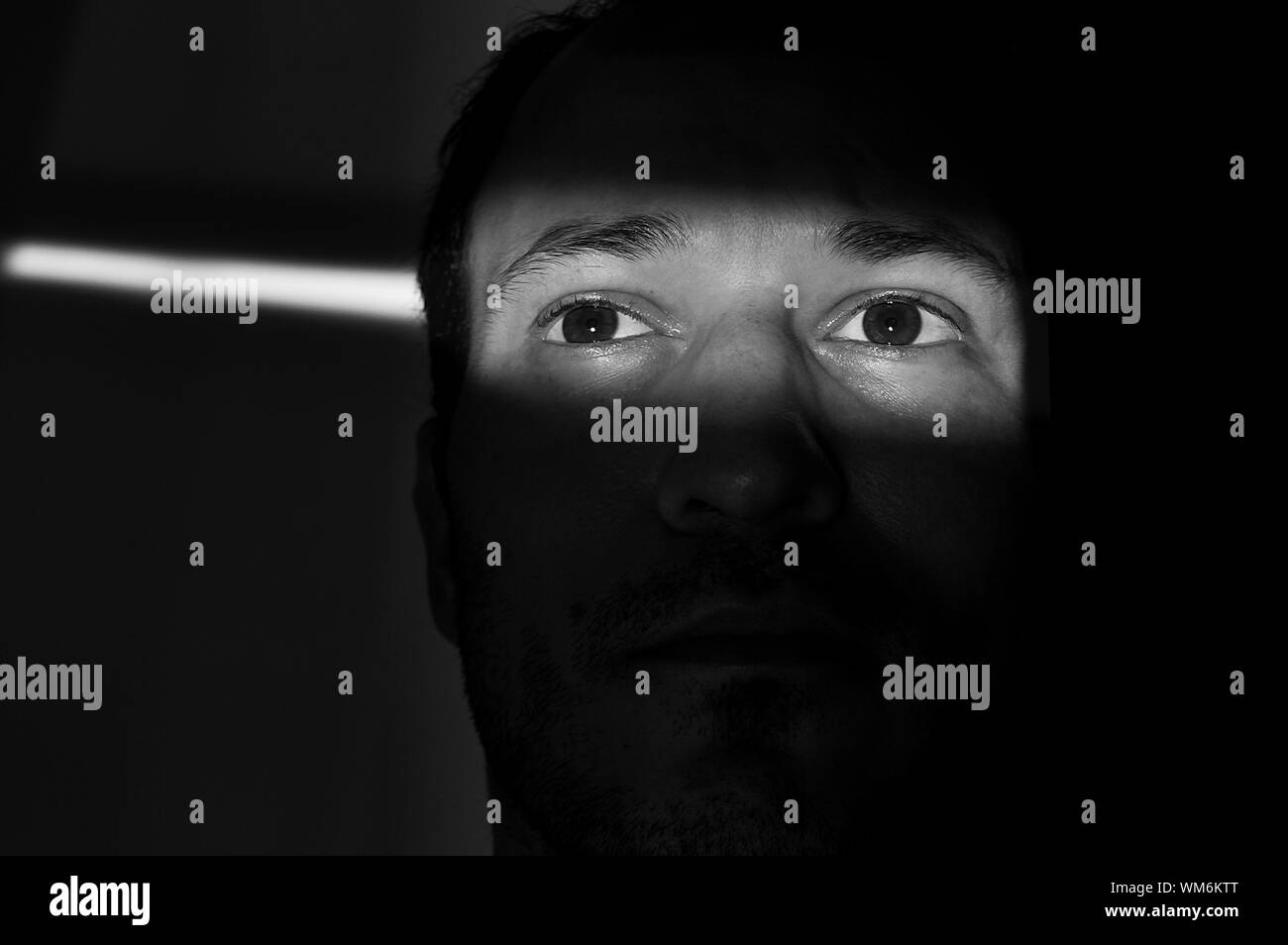 Closeup Of Man Looking Away Sitting In Dark Room Stock Photo Alamy