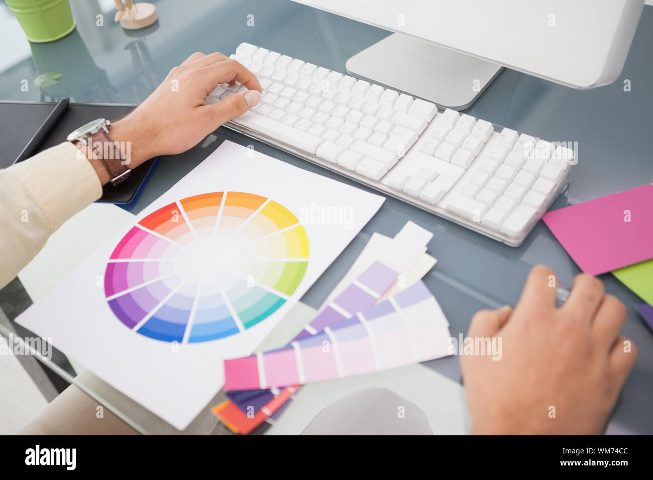 Designer using computer and colour wheel in his office Stock Photo - Alamy
