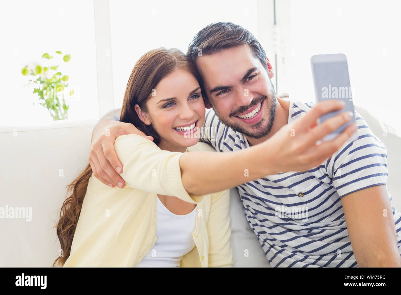 Cute couple taking a selfie on couch at home in the living room Stock ...