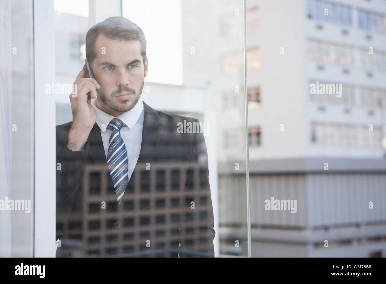 Businessman looking out window on the phone in his office Stock Photo ...