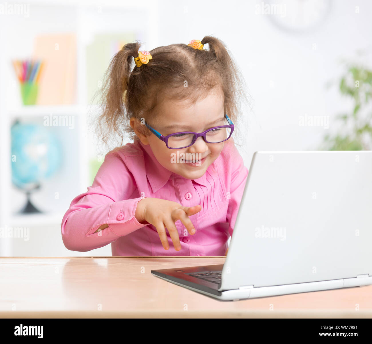 Happy kid in spectacles using notebook with great interest in school Stock Photo