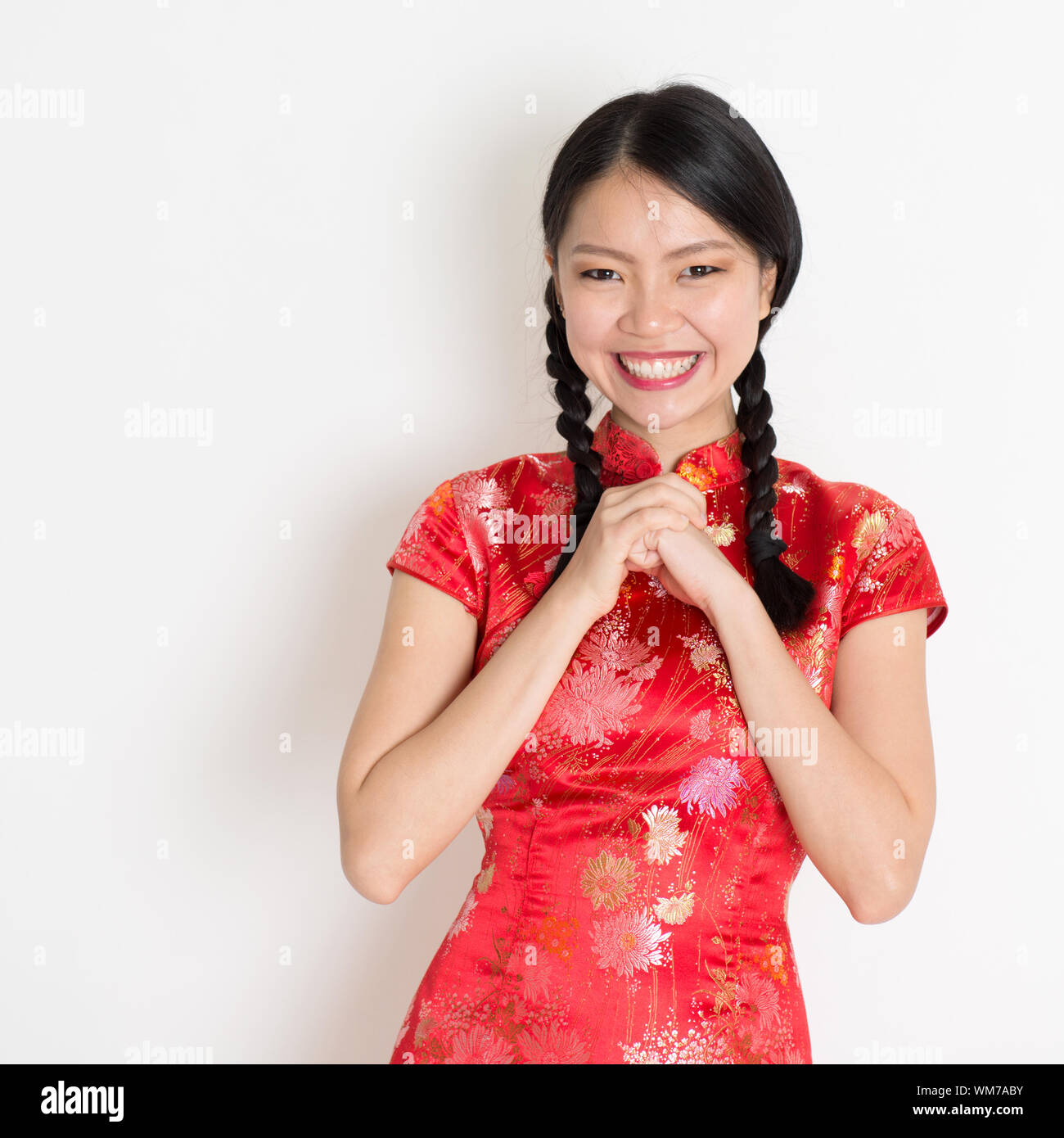Happy Chinese New Year!! Portrait of Asian Chinese girl greeting, in  traditional red qipao standing on plain background Stock Photo - Alamy