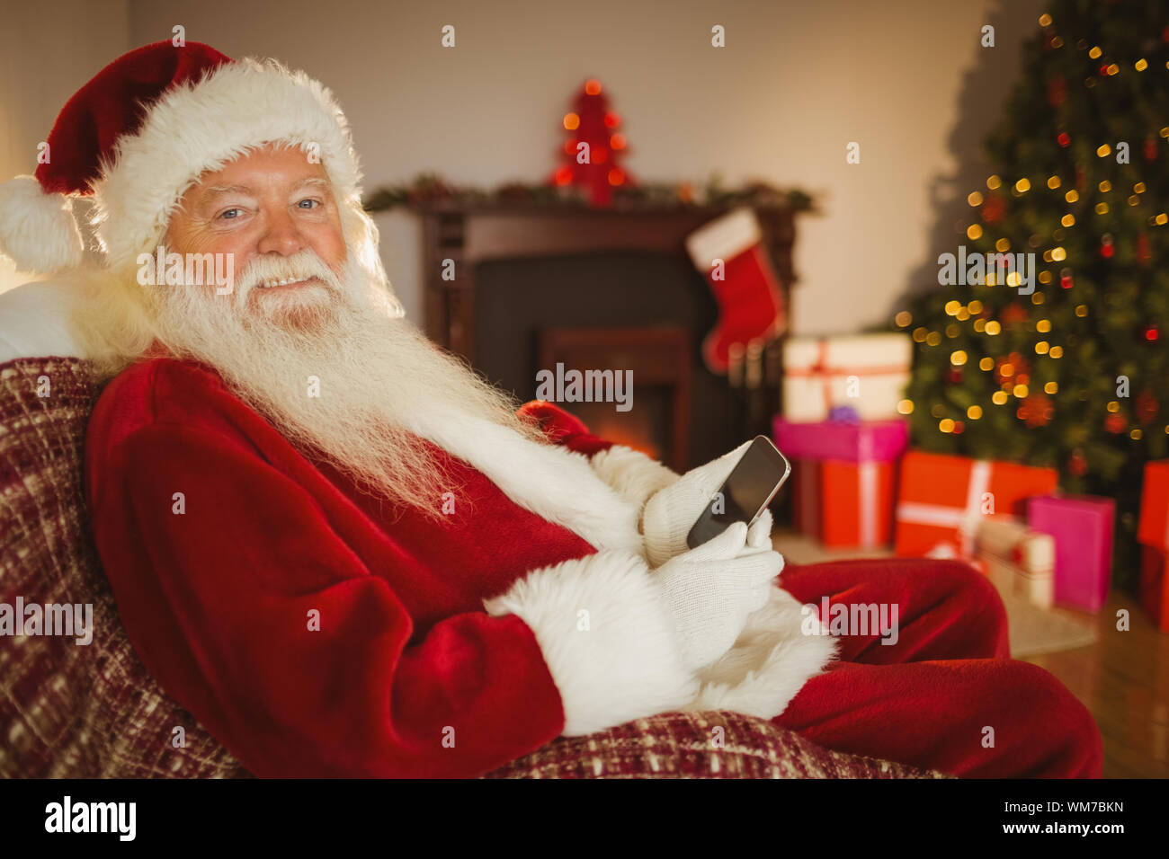 Smiling santa using smartphone at christmas at home in the living room ...