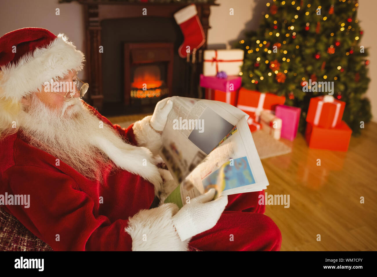 Father christmas reading newspaper on the couch at home in the living