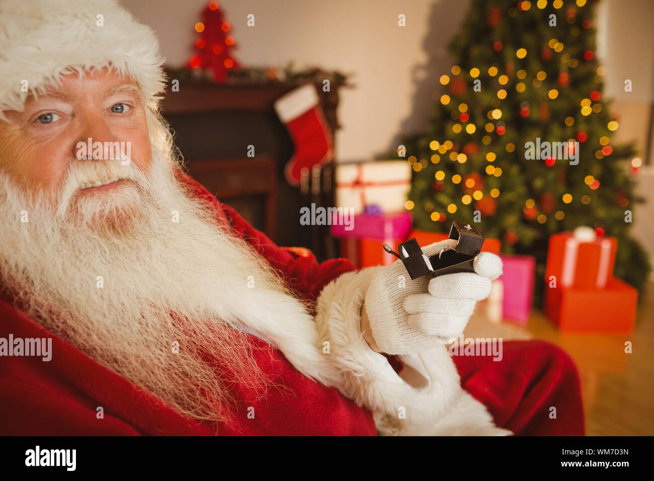 Father christmas holding engagement ring with his box at home in the