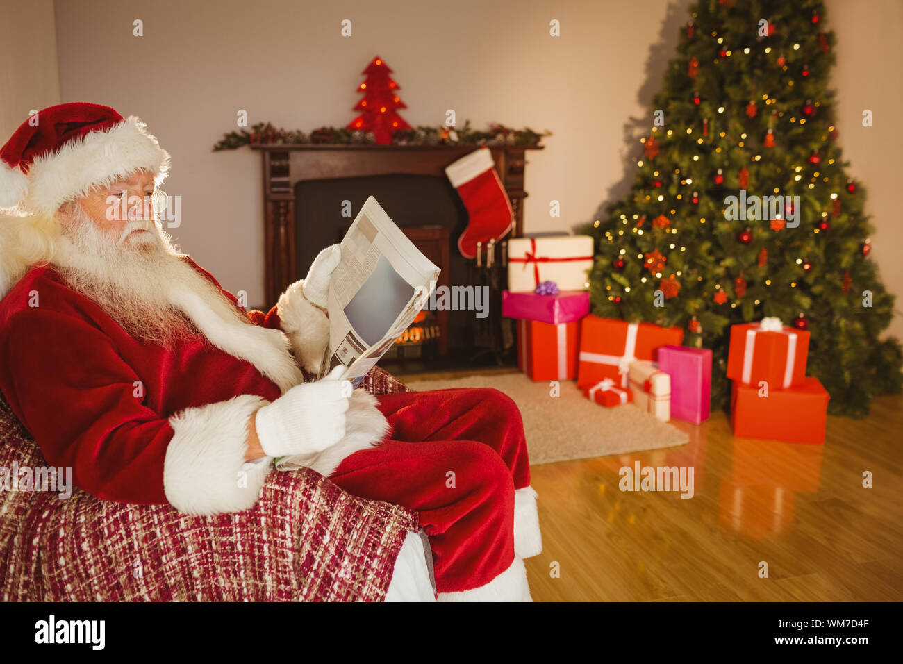 Santa Claus Reading Newspaper On The Couch At Home In The Living
