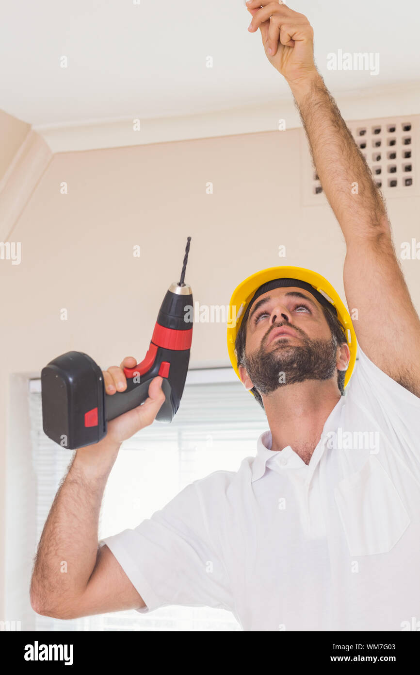 Construction worker drilling hole in ceiling in a new house Stock Photo
