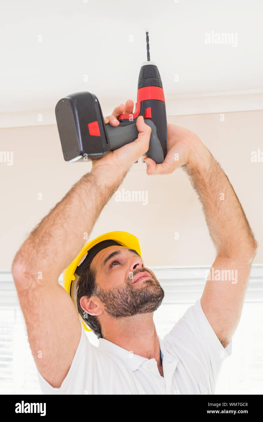 Construction worker drilling hole in ceiling in a new house Stock Photo