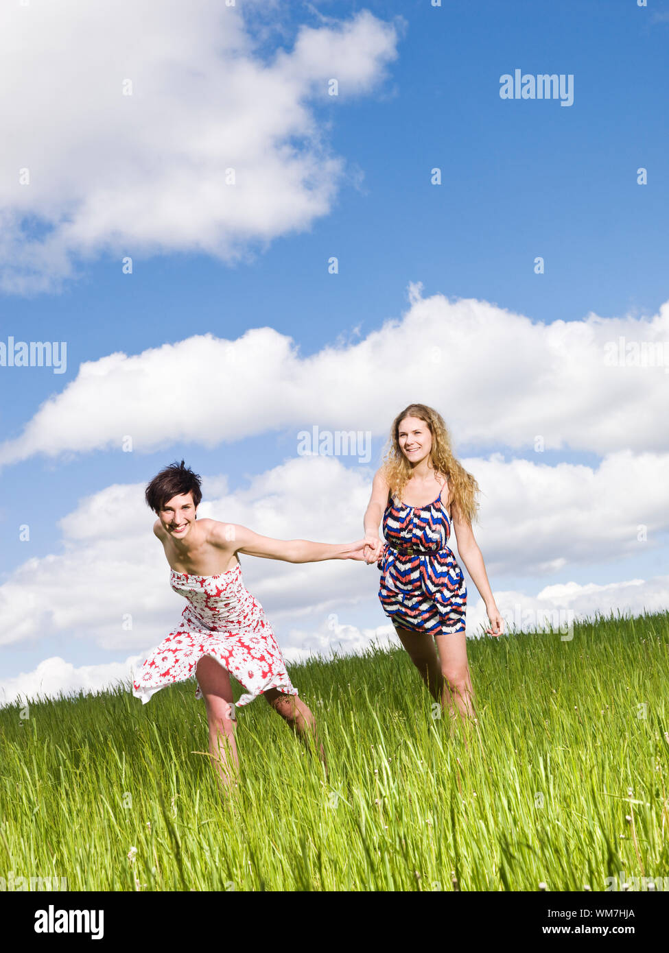 Two women holding hands on a field Stock Photo - Alamy