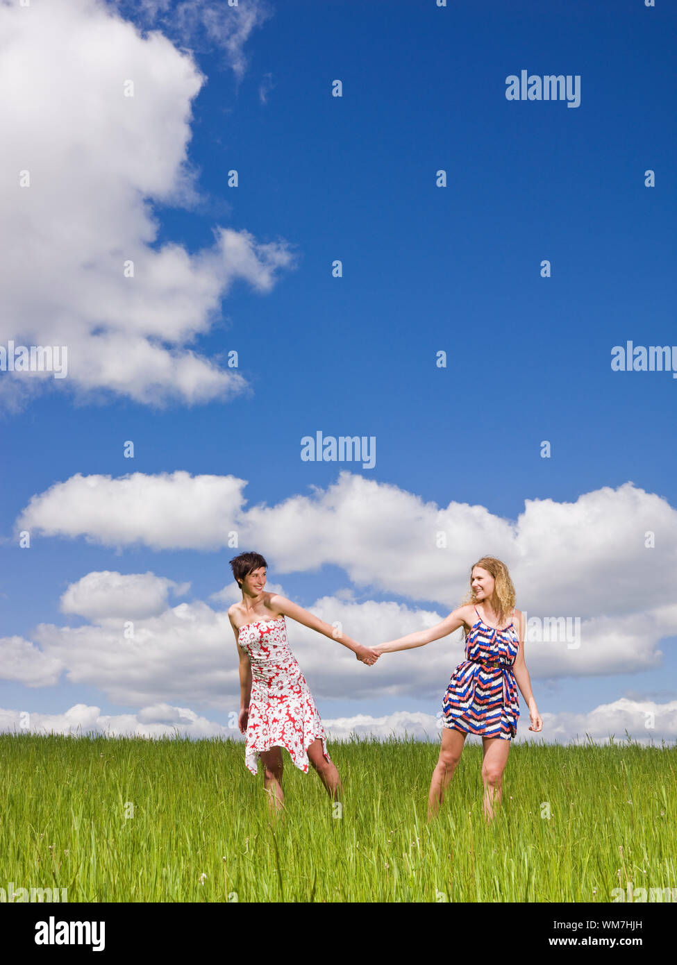 Two women holding hands on a field Stock Photo - Alamy