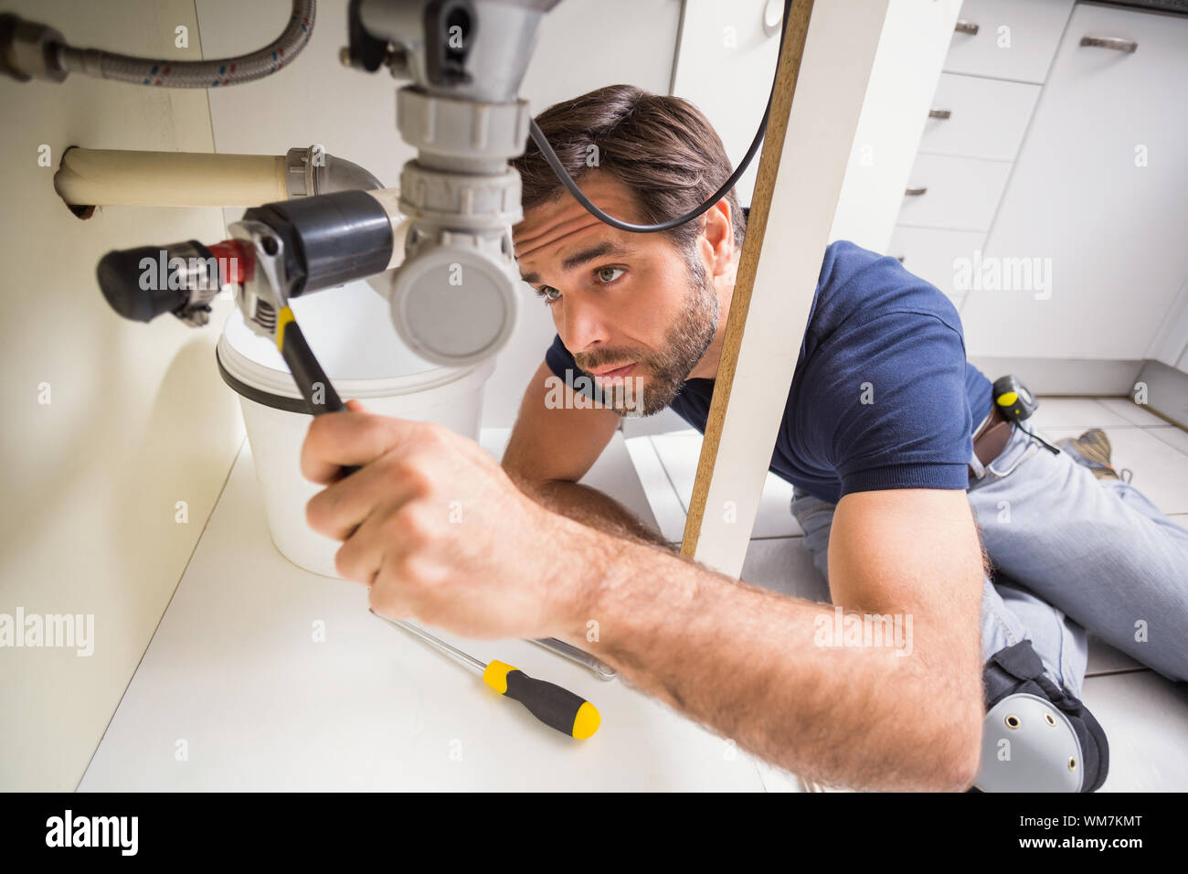 Plumber fixing under the sink in the kitchen Stock Photo