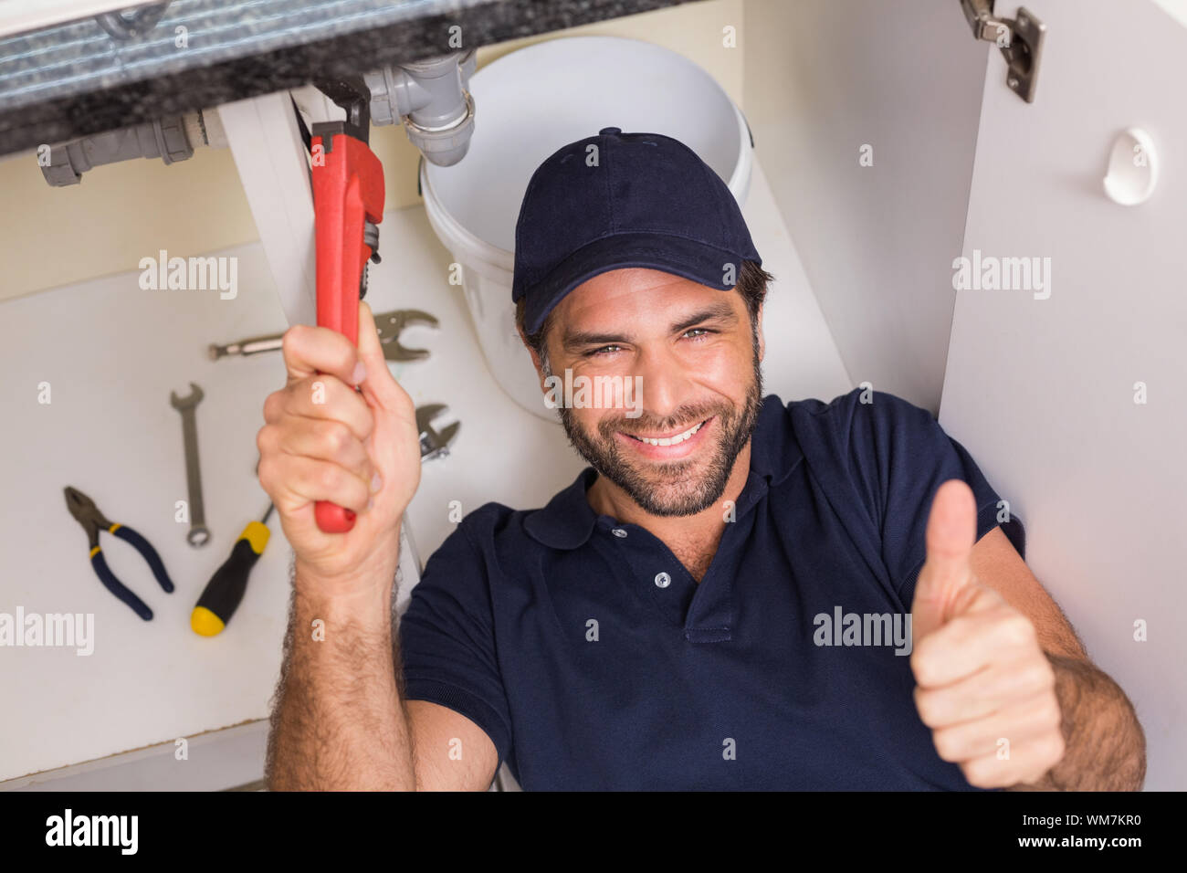 Plumber fixing under the sink in the kitchen Stock Photo