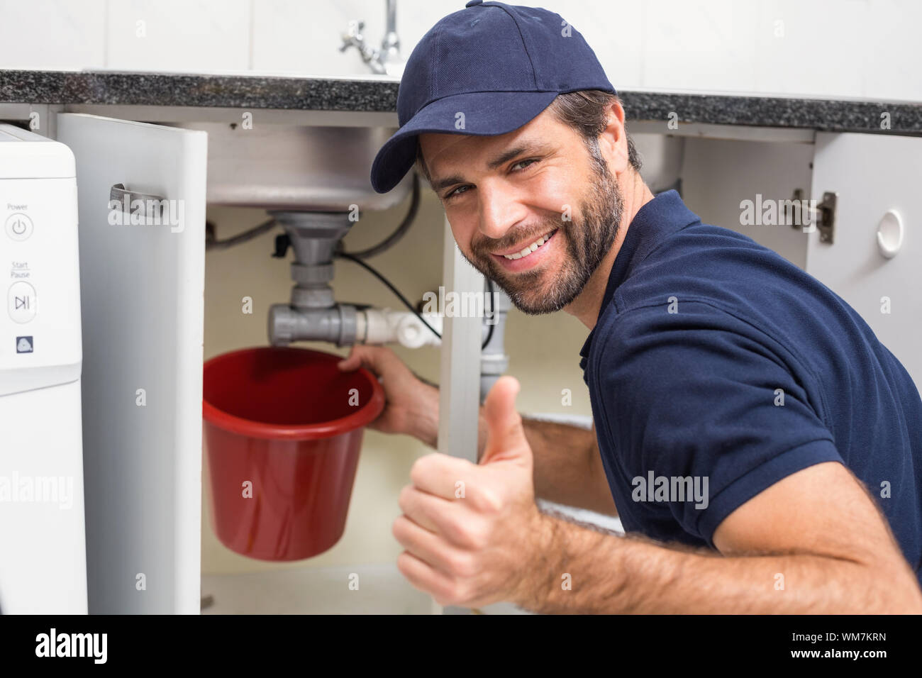 Plumber fixing under the sink in the kitchen Stock Photo