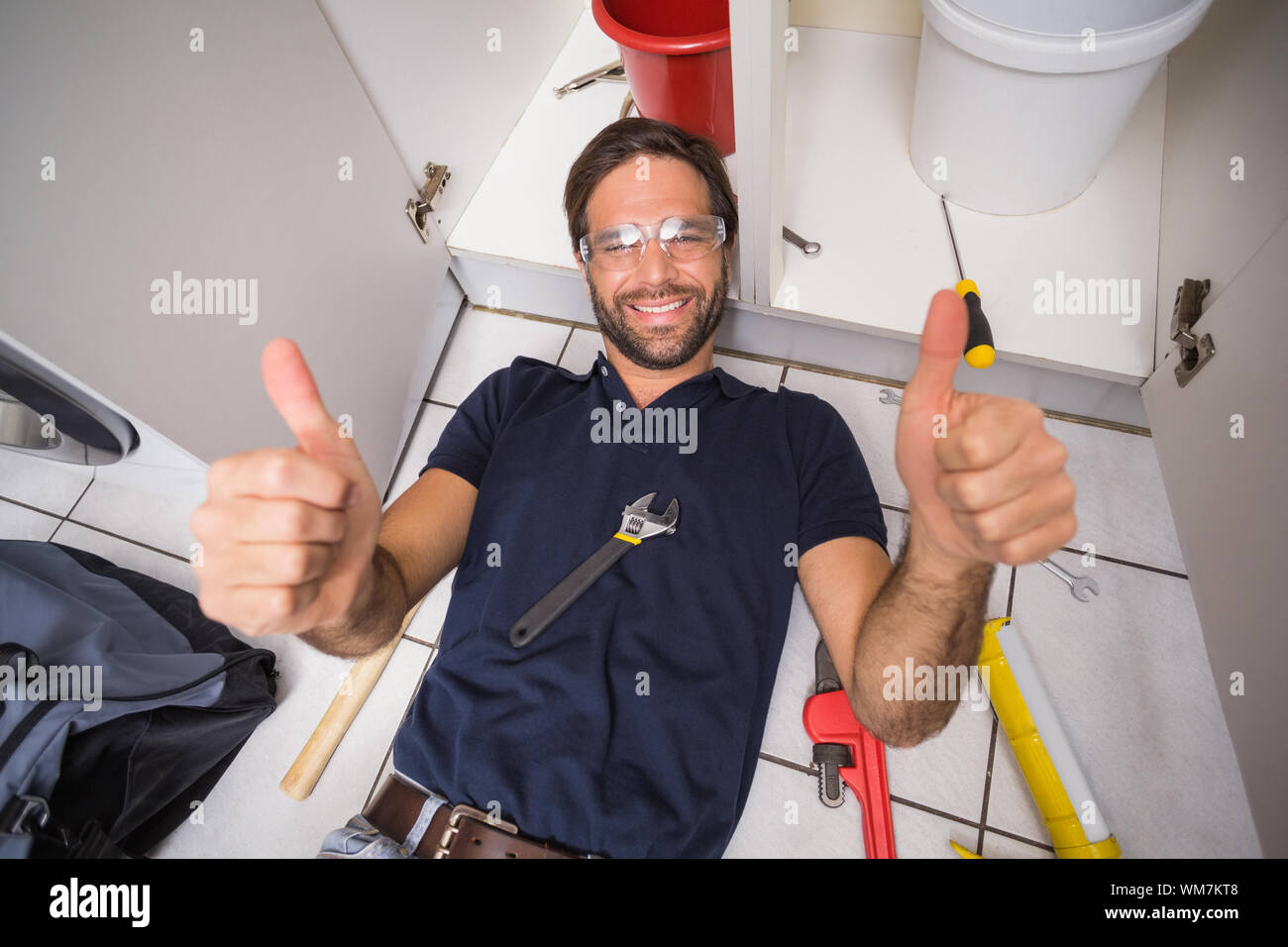 Plumber fixing under the sink in the kitchen Stock Photo