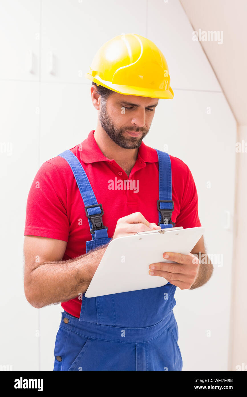 Construction worker taking notes on clipboard in a new house Stock Photo