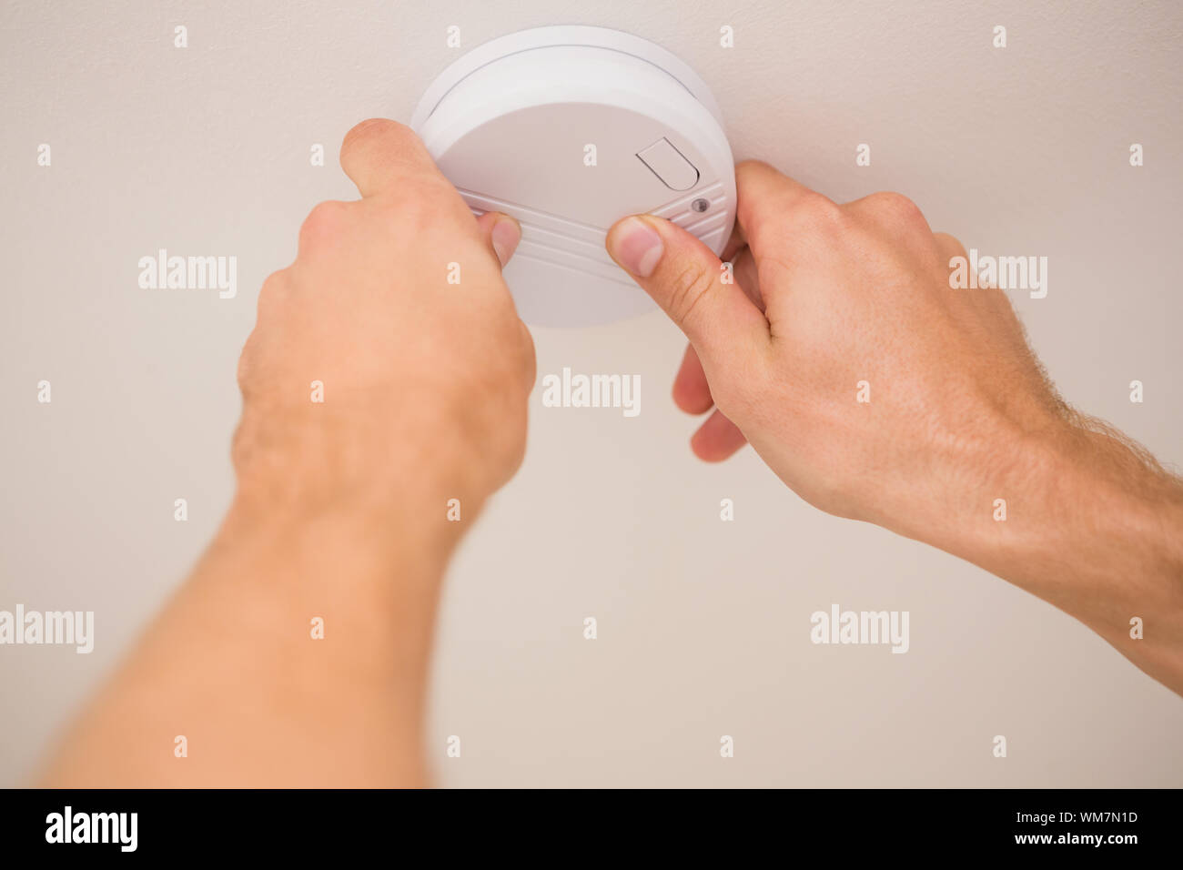 Handyman installing a smoke detector on the ceiling Stock Photo