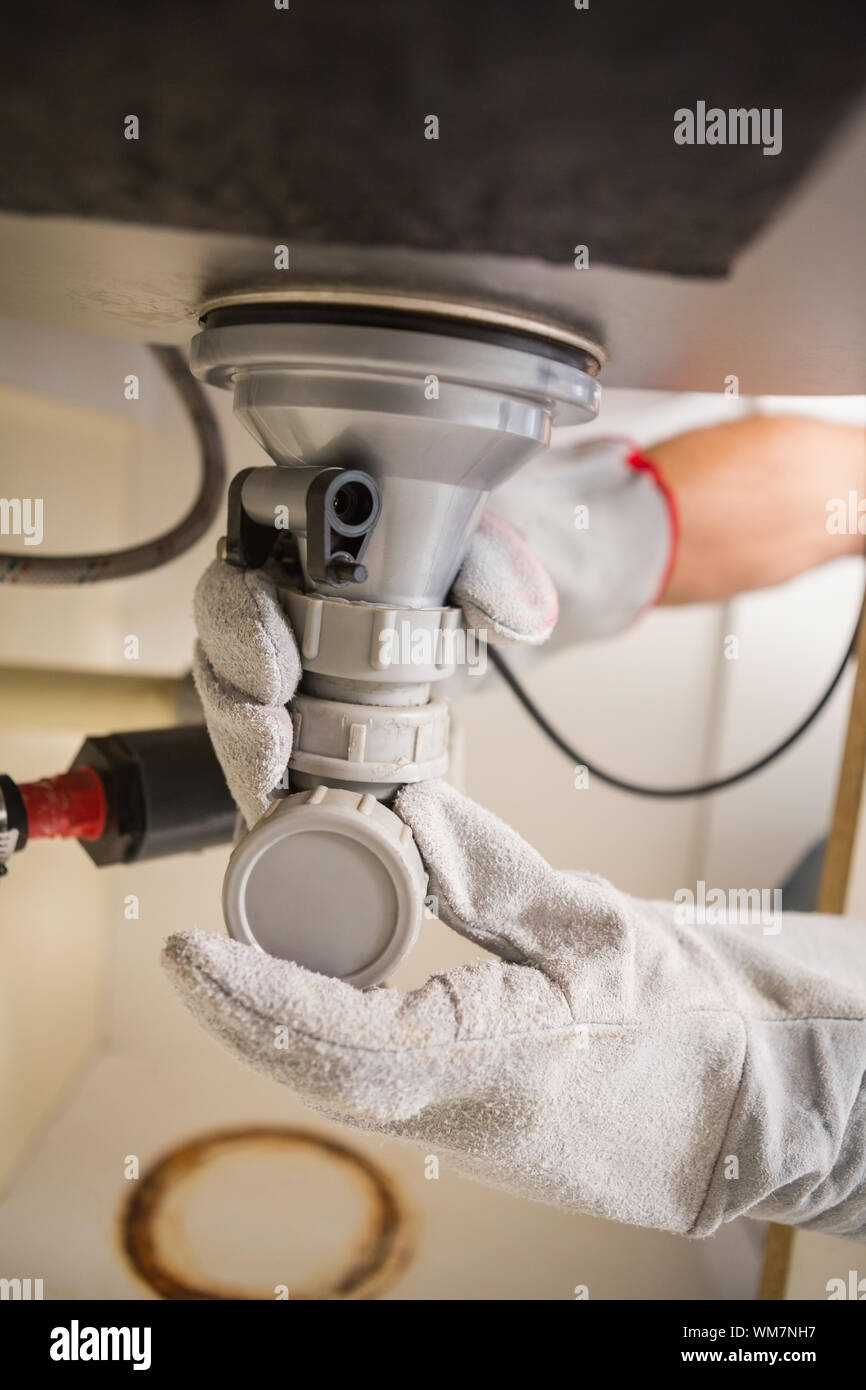 Plumber fixing under the sink in the kitchen Stock Photo