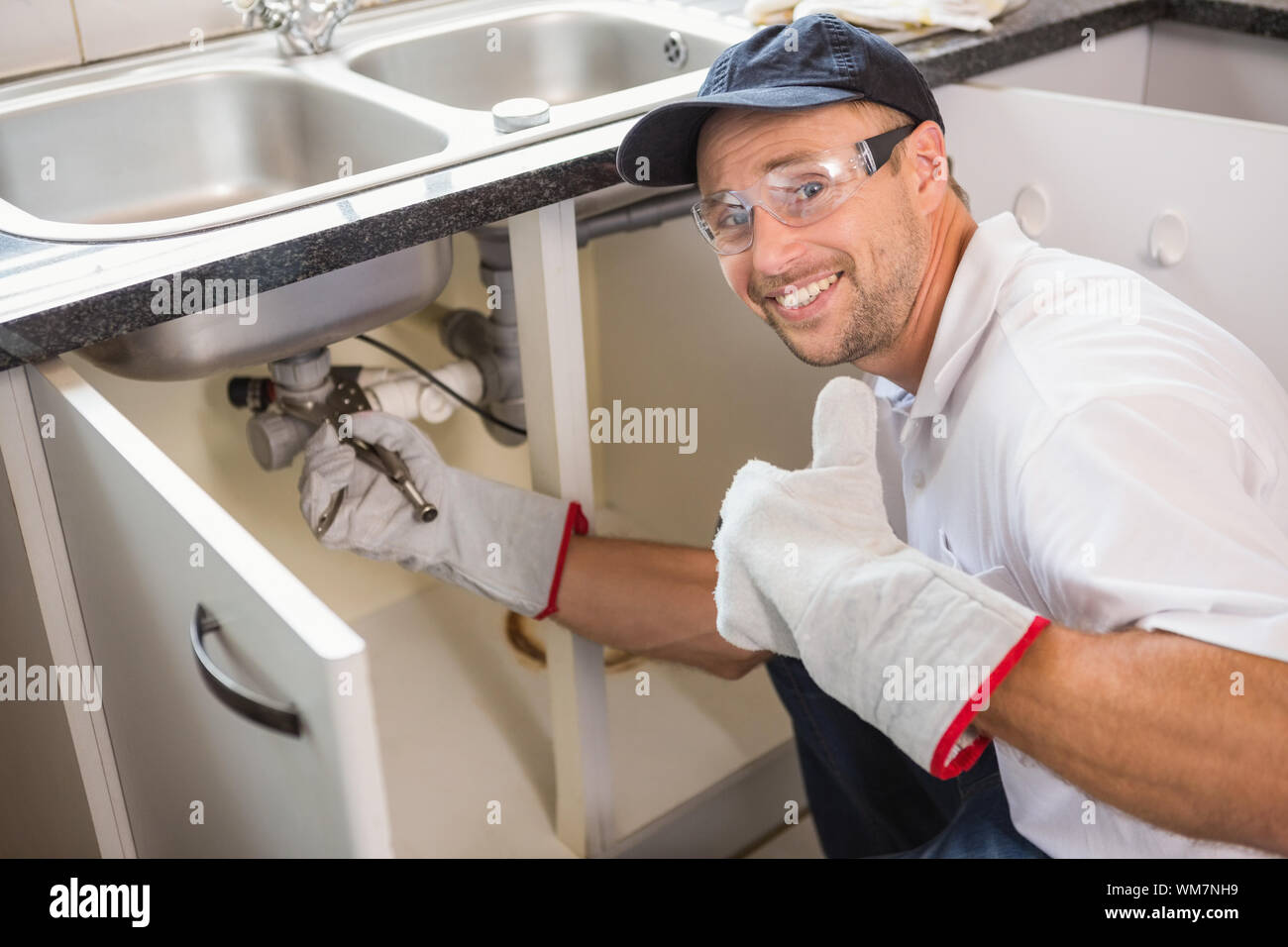 Plumber fixing under the sink in the kitchen Stock Photo