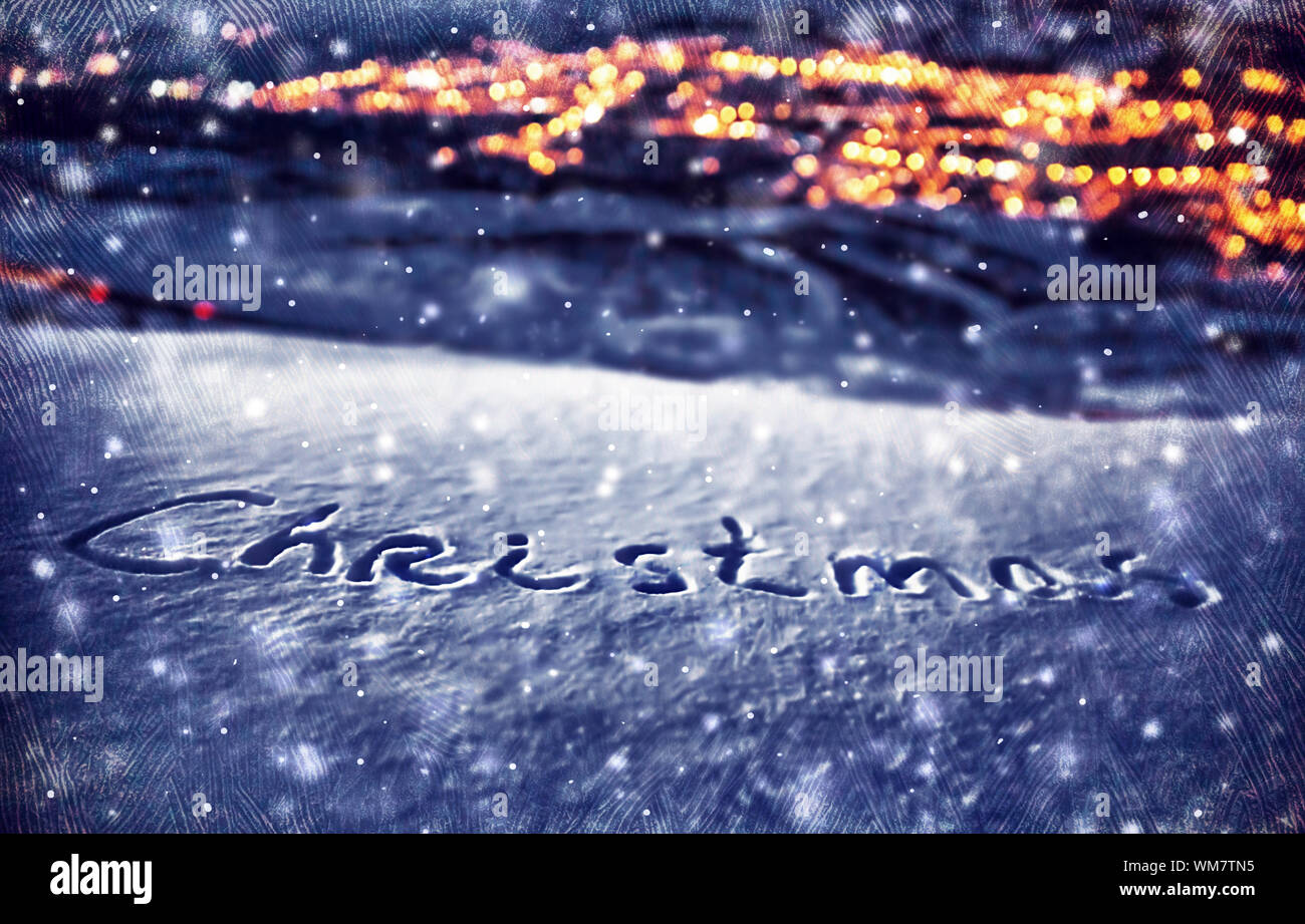Christmas background, handwriting on the snow, beautiful winter at night, Xmas holidays theme, dark textured photo, focus on th Stock Photo -