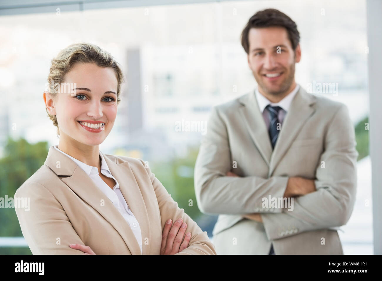 Business people posing with arms crossed smiling at camera in office ...