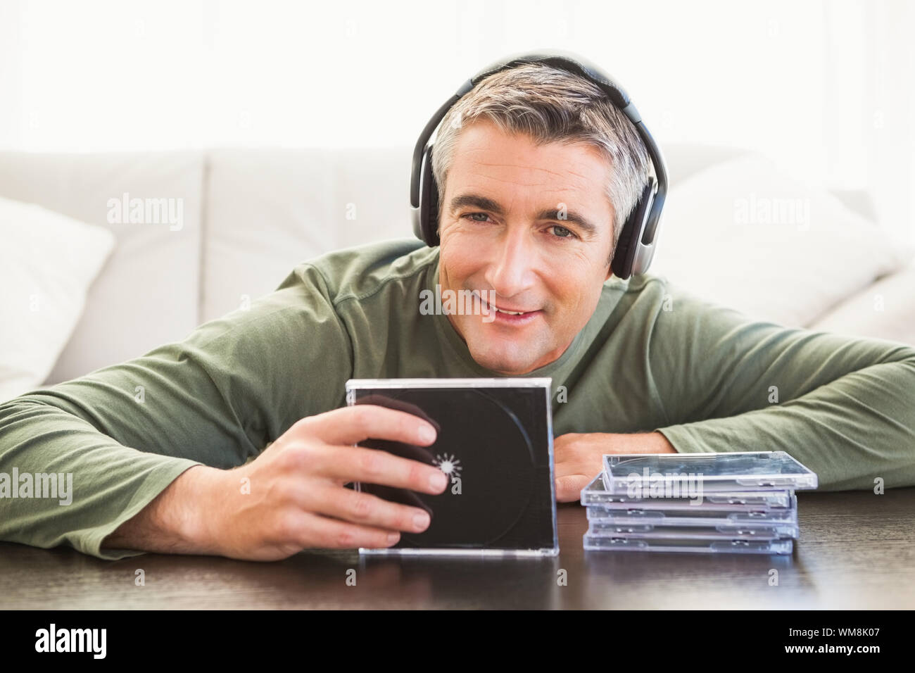 Smiling man listening music and holding cd at home in the living room Stock Photo