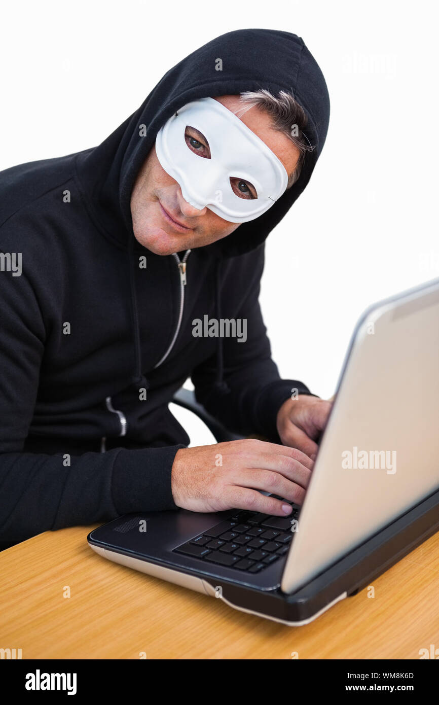Hacker with white mask using laptop and looking at camera on white background Stock Photo