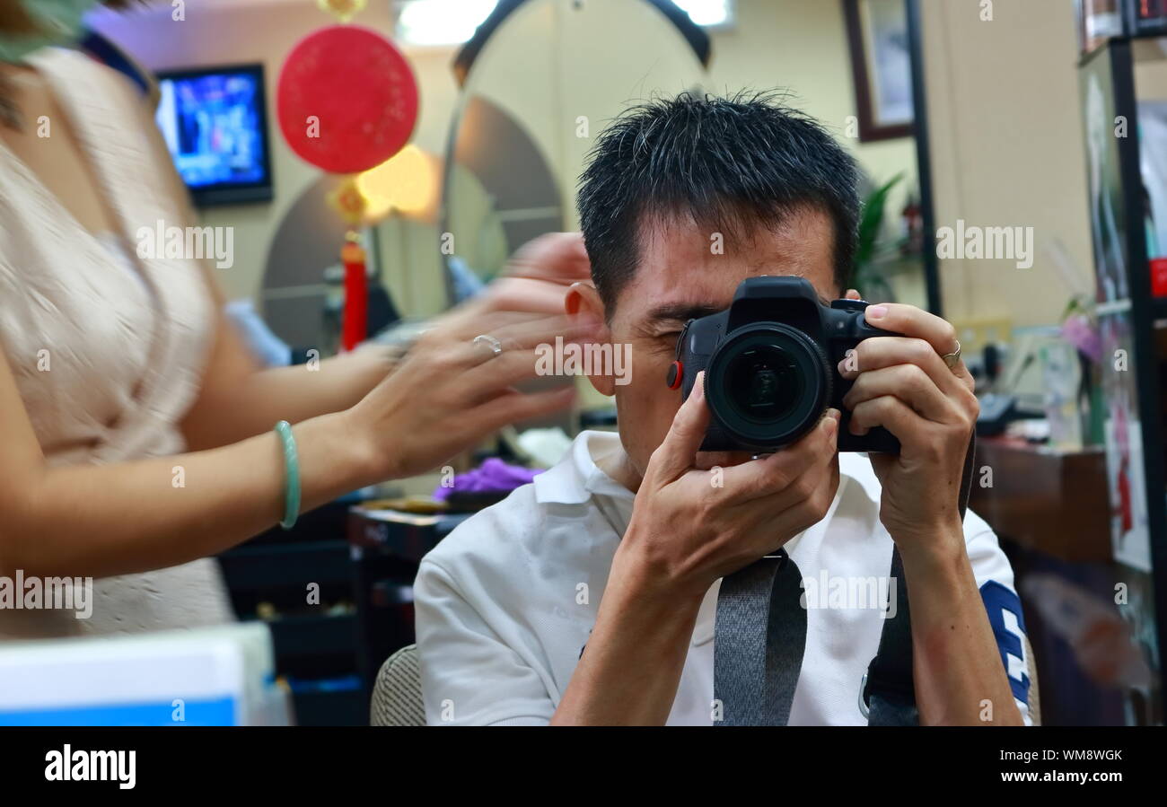 I am taking image of myself in the mirror with DSLR camera during having a hair cut Stock Photo